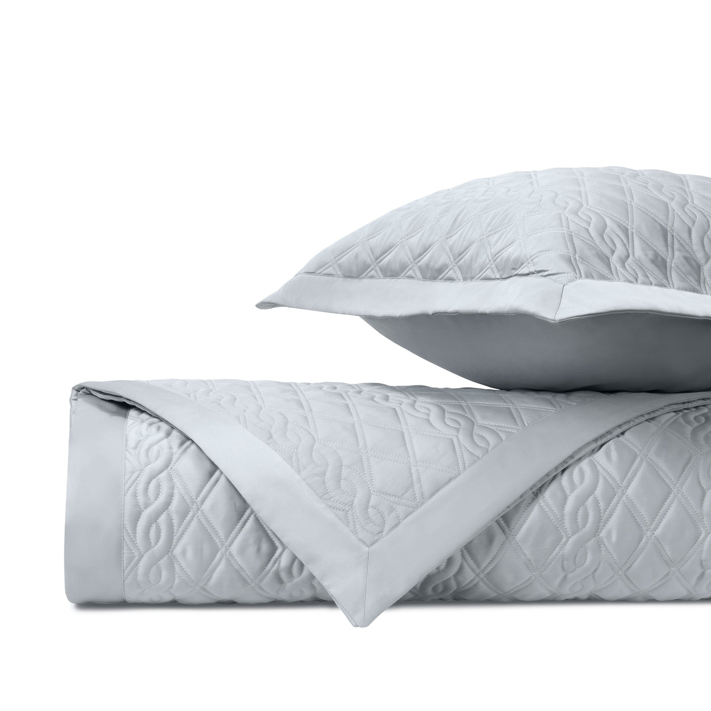 Folded silver quilted fabric with diamond and vine stitching, shown with a coordinating sham.