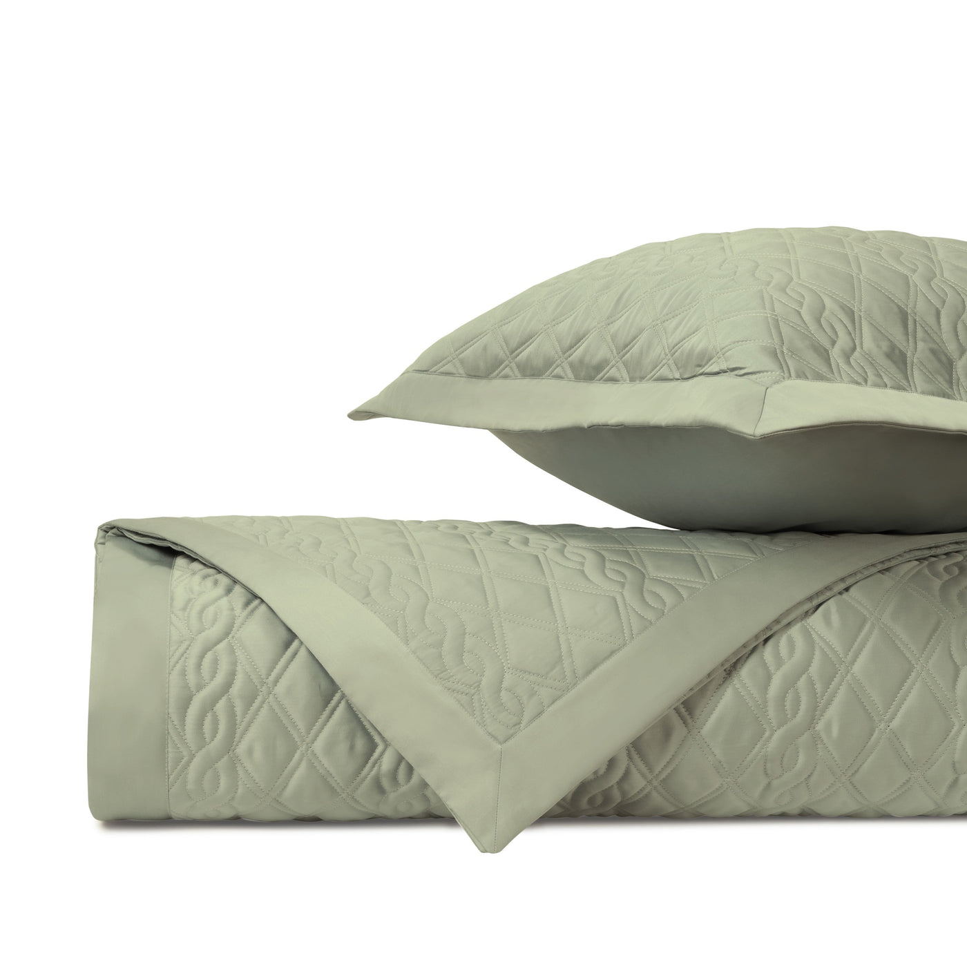 Folded sage green quilted coverlet with geometric stitching and matching sham.