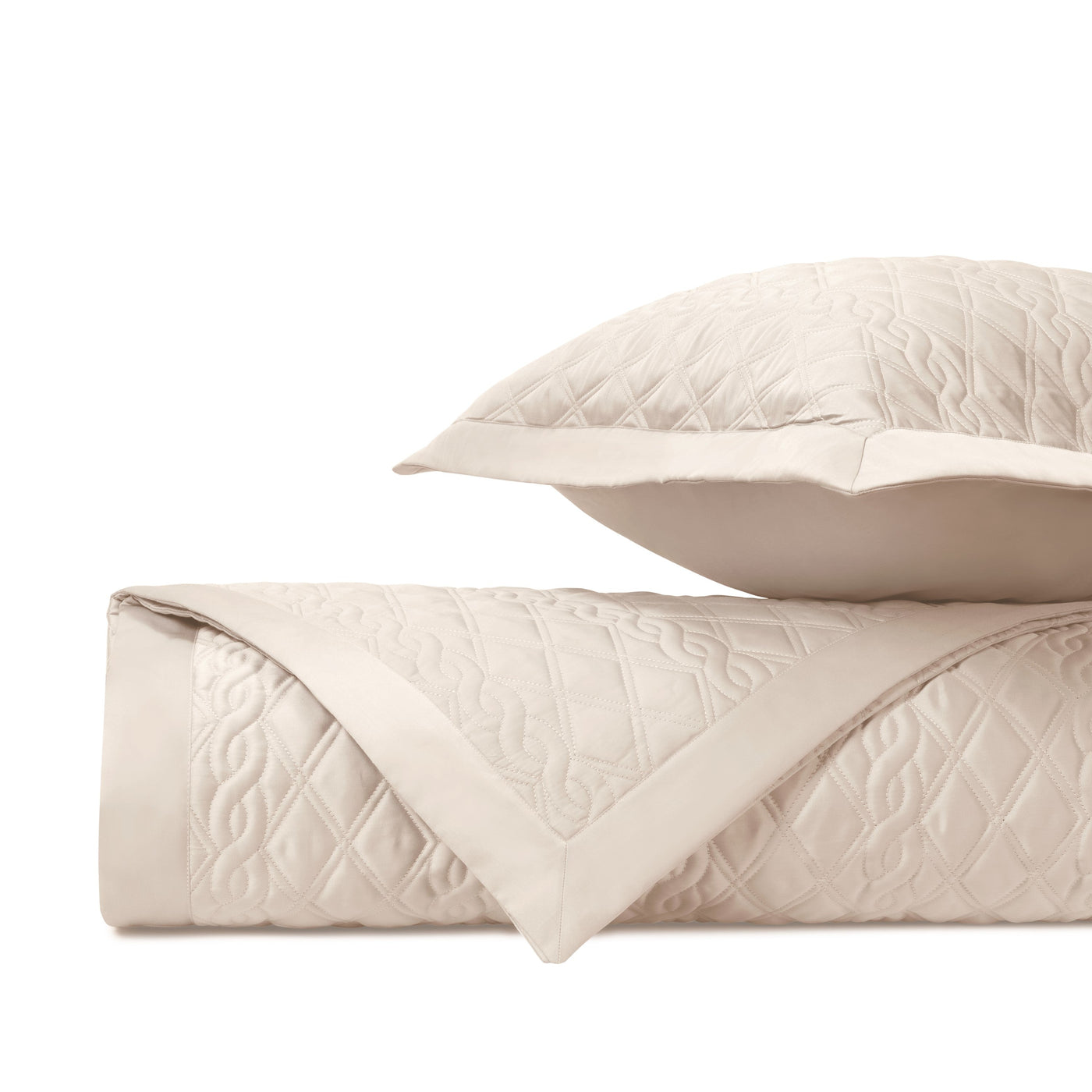 Close-up of Abbey quilted coverlet corner showing ivory diamond and scroll stitching detail.
