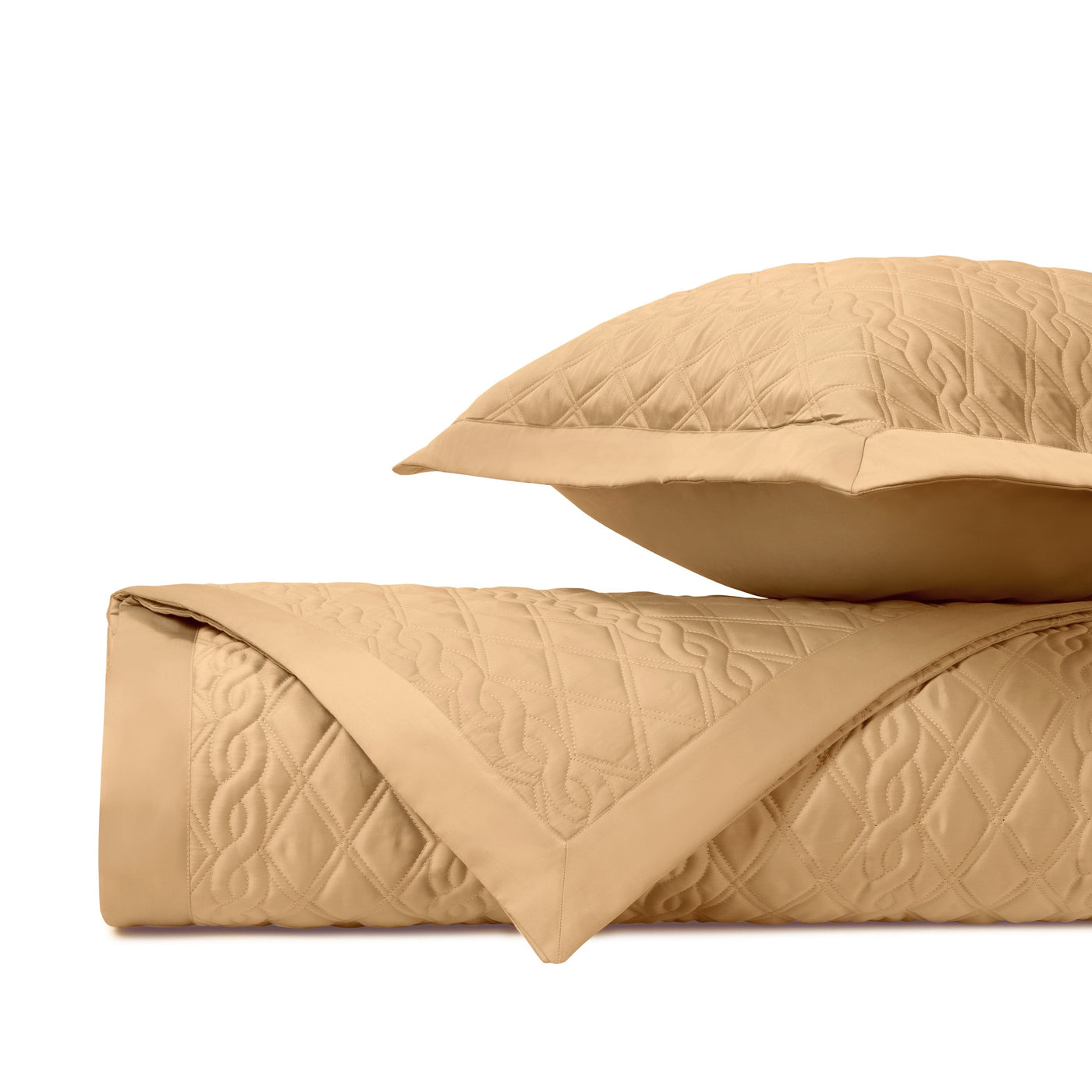 Caramel quilted coverlet and sham folded, showing diamond and scroll stitch detail.