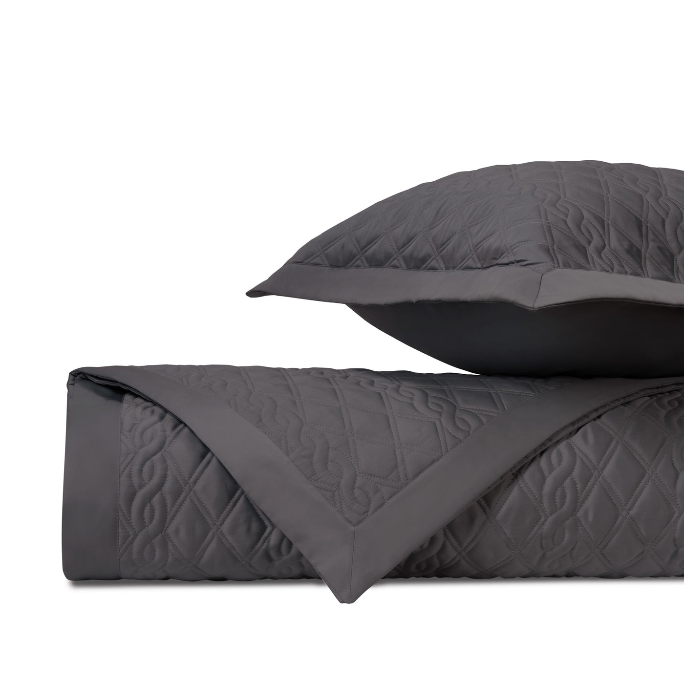 Close-up of charcoal quilted coverlet with diamond and scroll stitching pattern, folded with matching euro sham.
