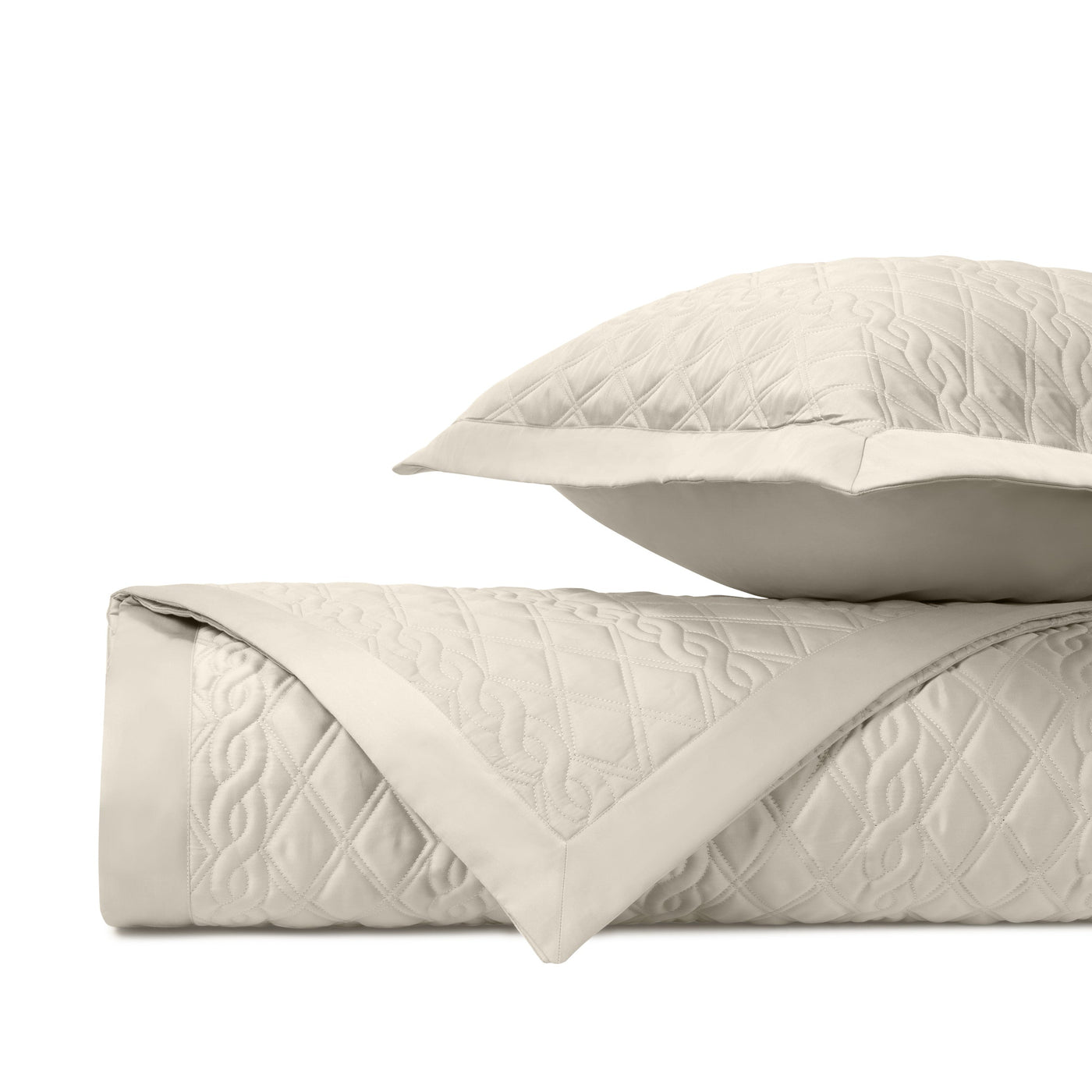 Close-up of Abbey ivory quilted coverlet and sham showing intricate scrollwork stitching detail.