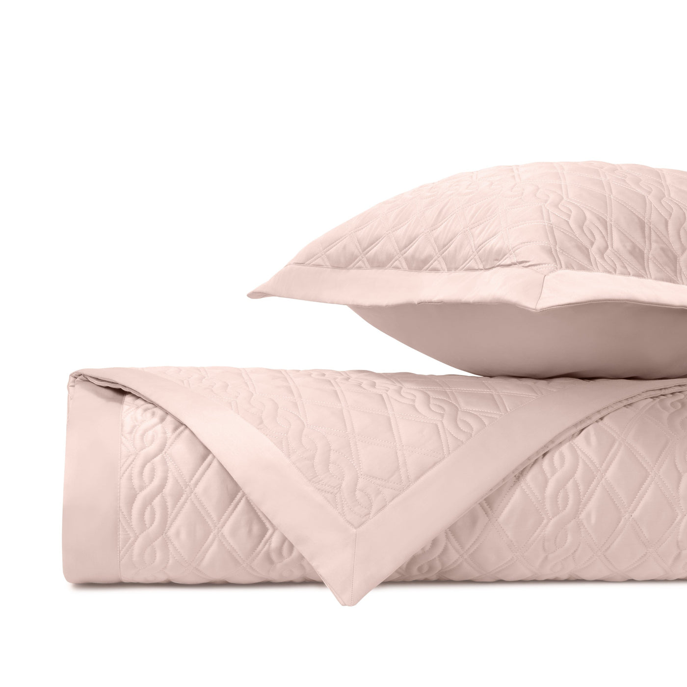 Folded blush quilted fabric with diamond and scroll stitching, shown with a matching sham.