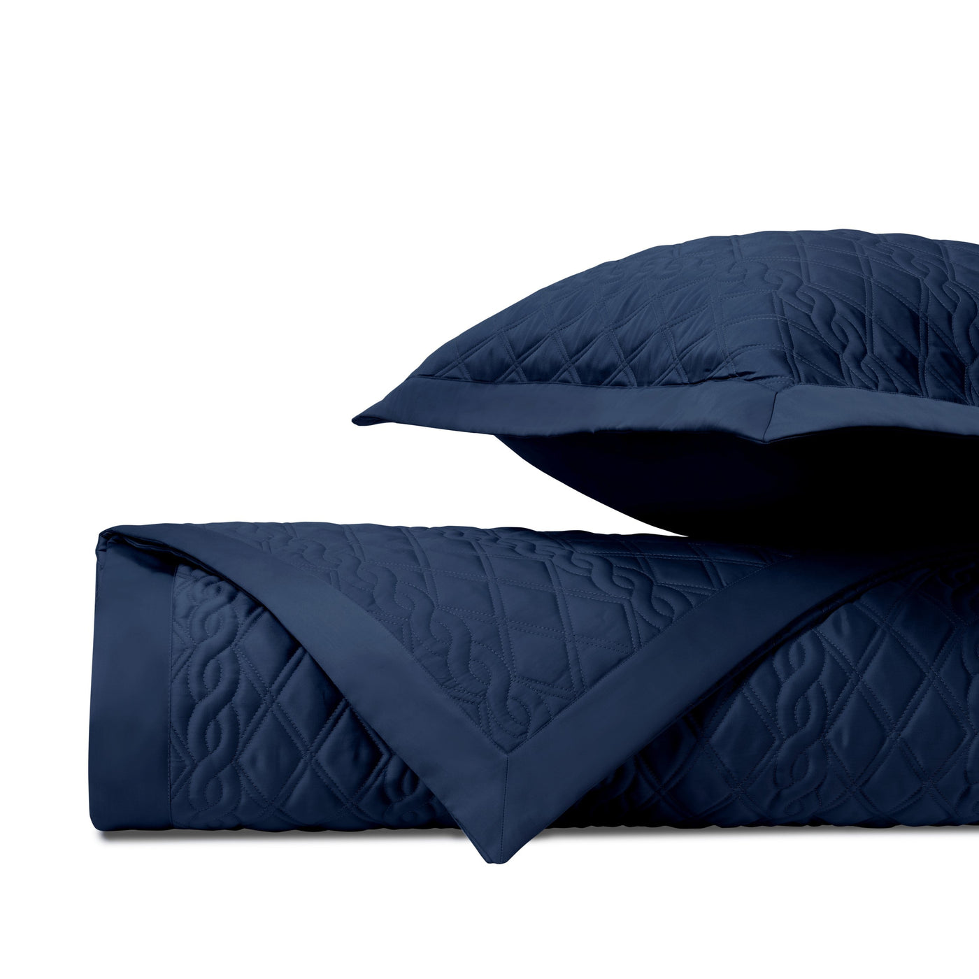 Navy blue quilted coverlet folded with matching sham, showing diamond stitch pattern detail.