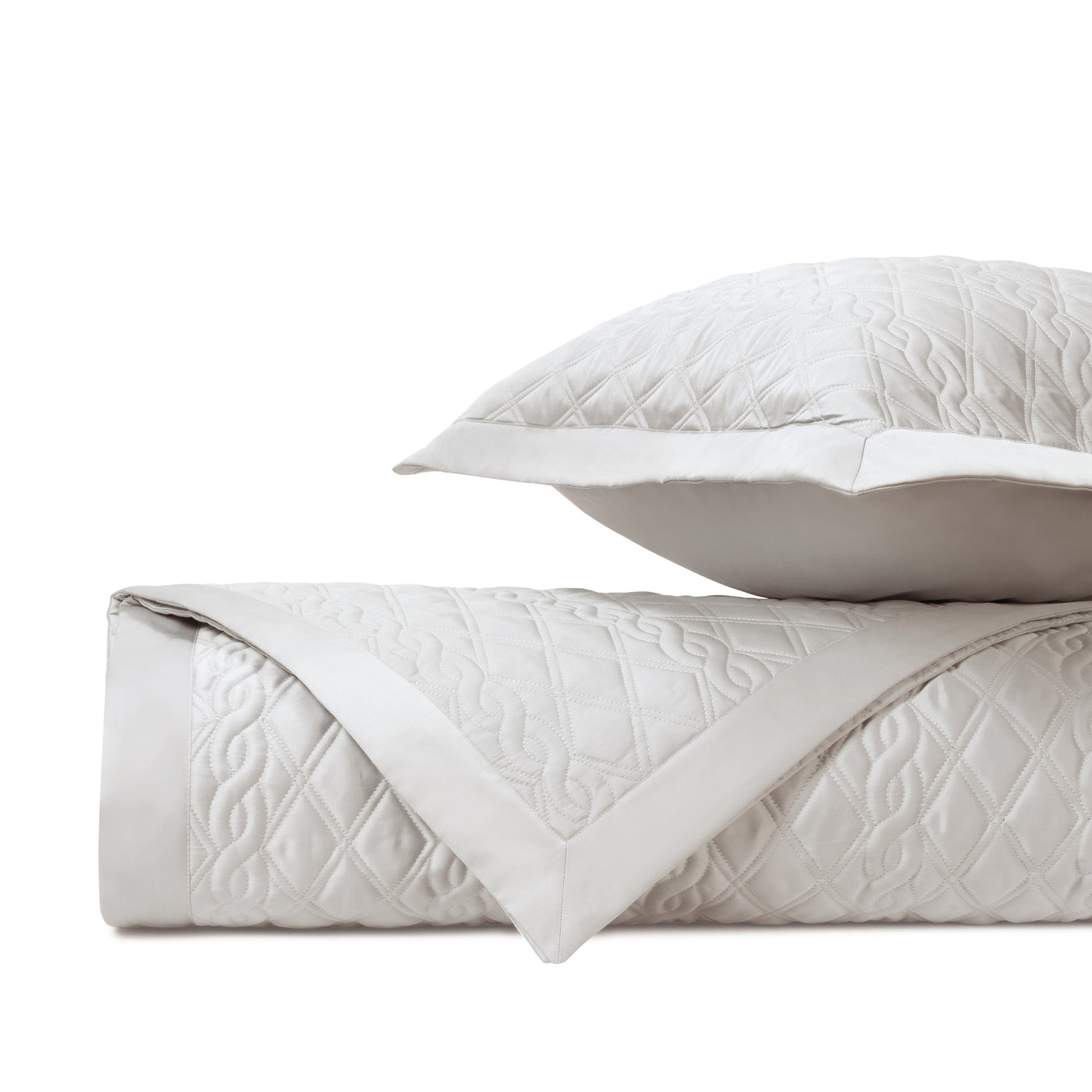 Close-up of Abbey quilted coverlet folded edge showing diamond and scroll stitching in ivory.