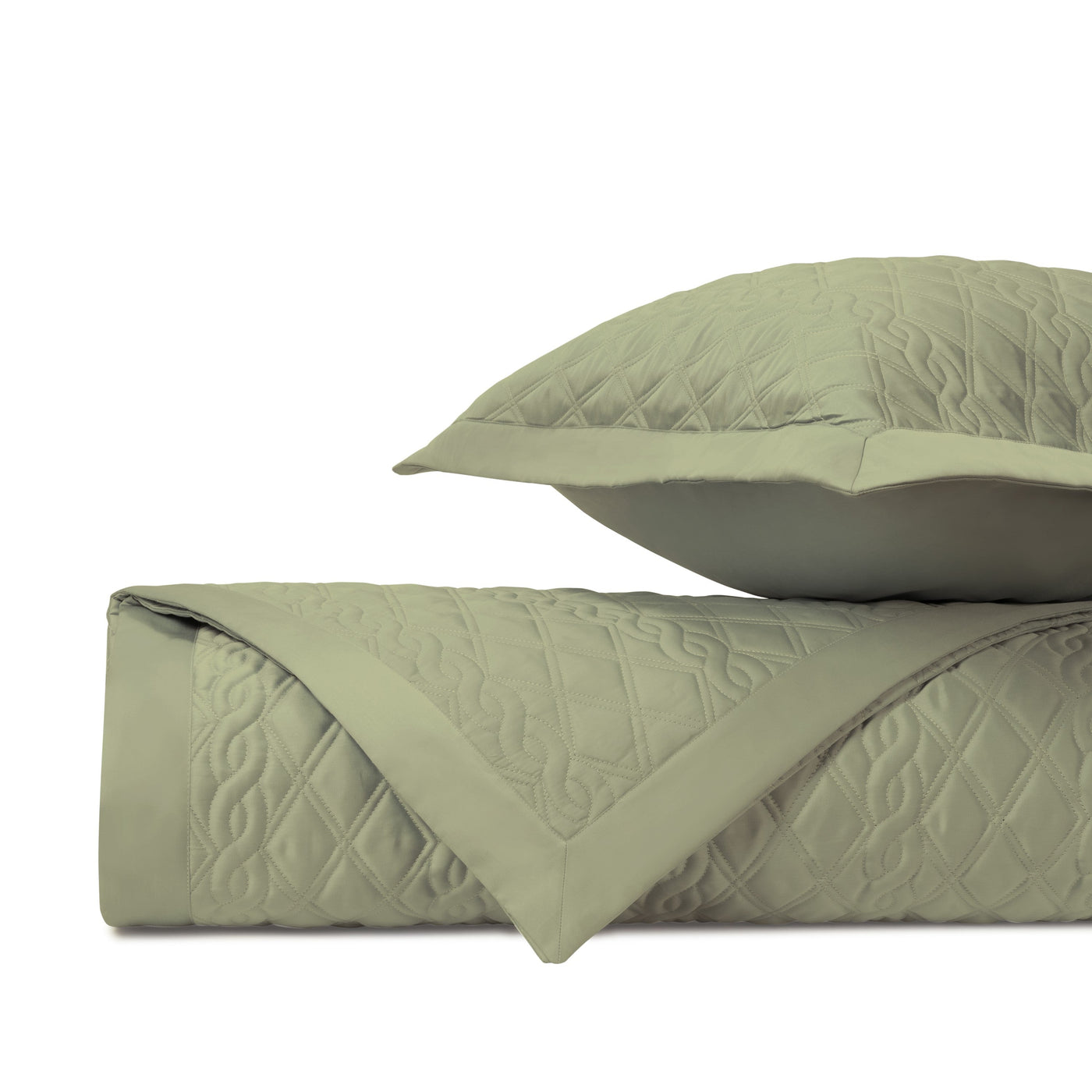 Close-up of Abbey quilted coverlet corner fold showing diamond and scroll stitching in sage green.