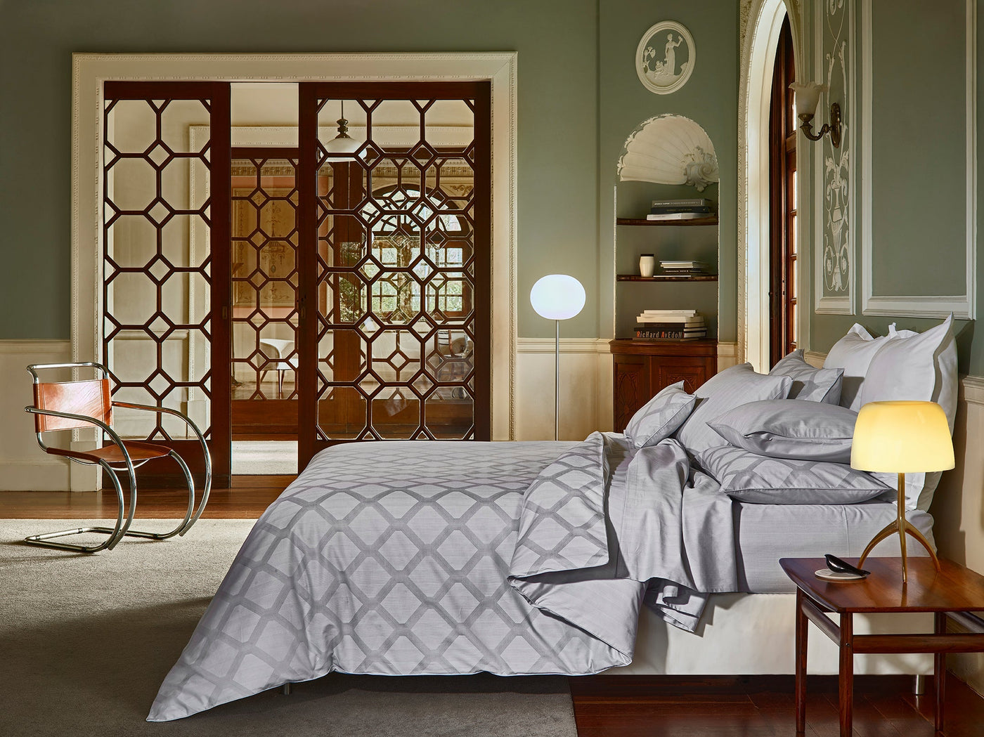 Silver geometric lattice duvet cover styled on bed in elegant green-walled room.