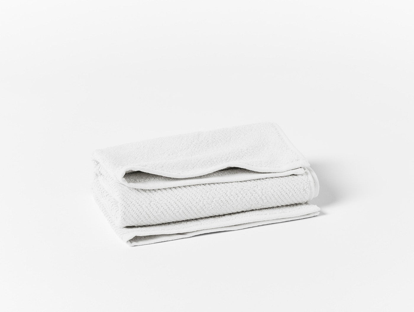 Coyuchi Air Weight wash cloth folded, white with subtle herringbone texture.