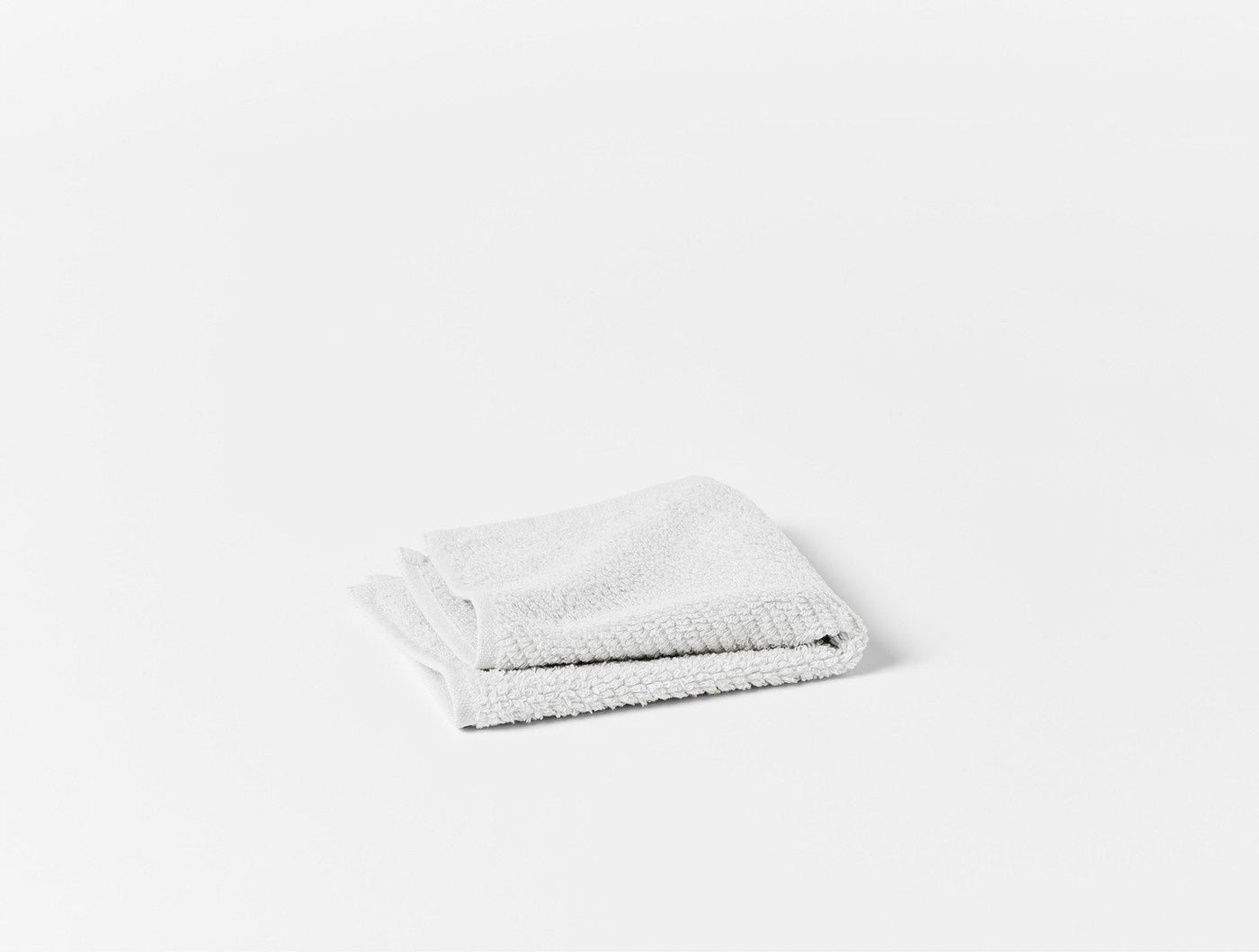 Folded white terry washcloth with dense looped pile, isolated on white background.