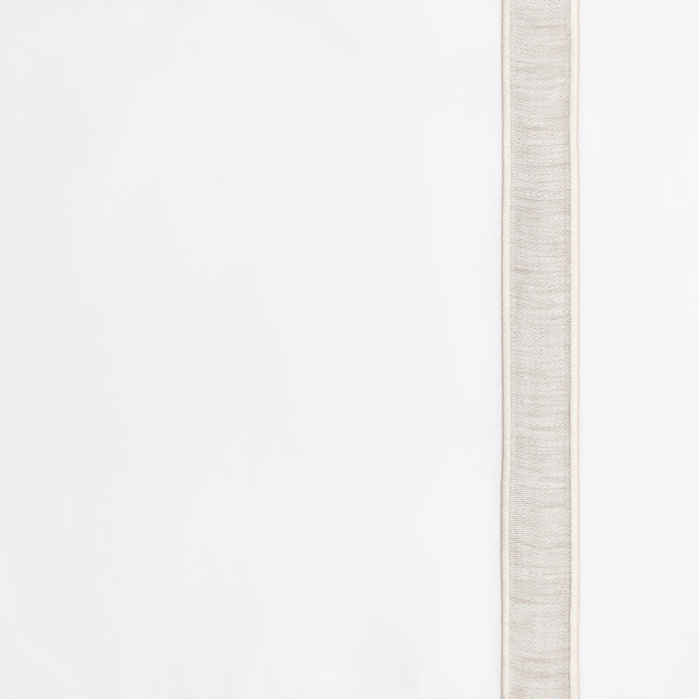 Close-up of woven natural linen border trim along white tablecloth edge.