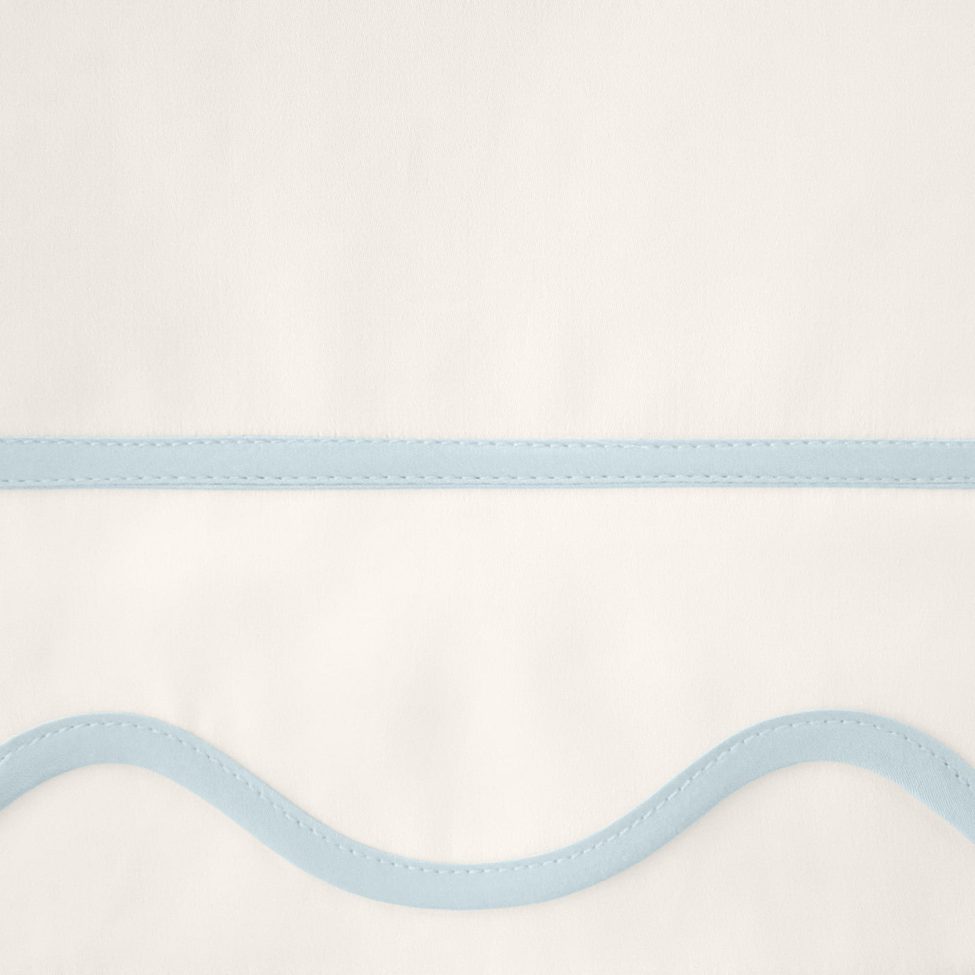 Close-up of ivory fabric with powder blue wavy satin border trim detail.