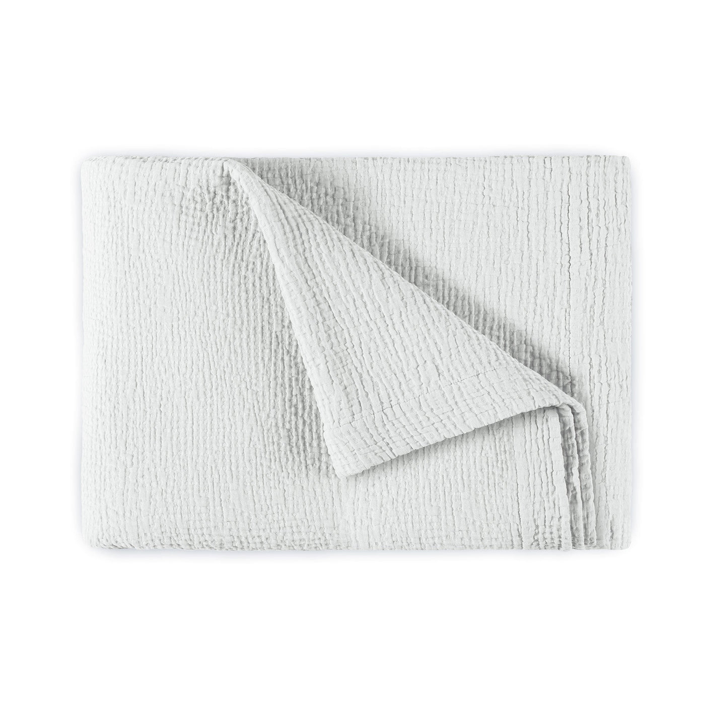 Corner fold detail revealing textured ivory cotton weave on Areia bedspread.