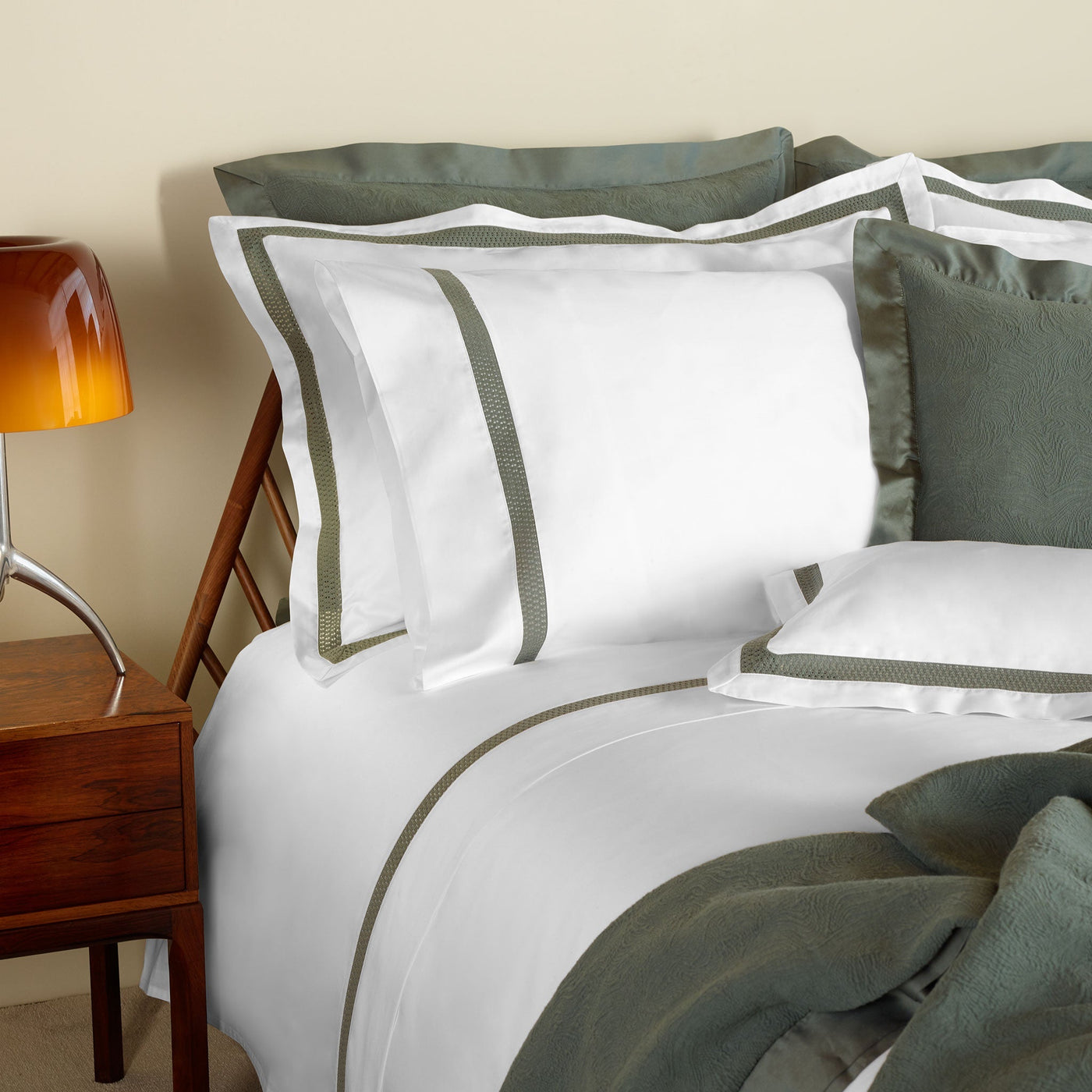 Neatly made bed with white sheets and green decorative pillows in a bedroom setting.