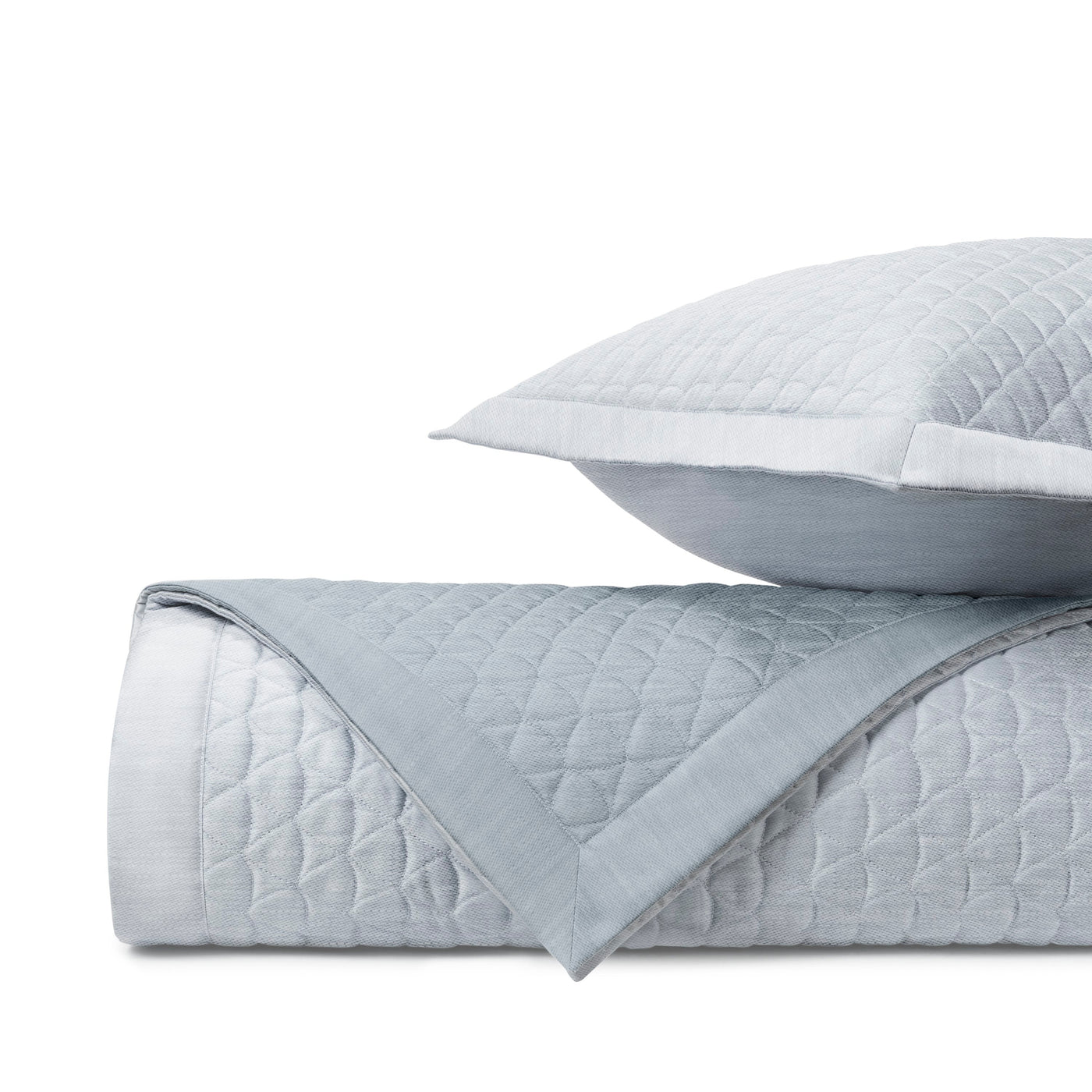 Folded quilted coverlet in mist blue with diamond stitching and satin trim detail.