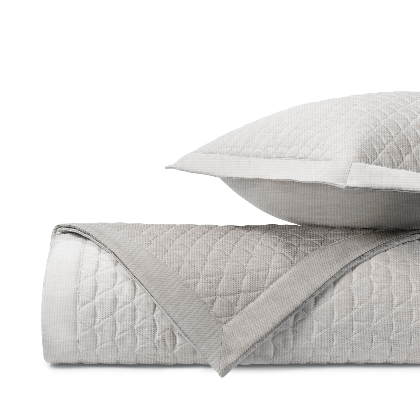 Rolled silver quilted coverlet with diamond stitching beside a matching euro sham.