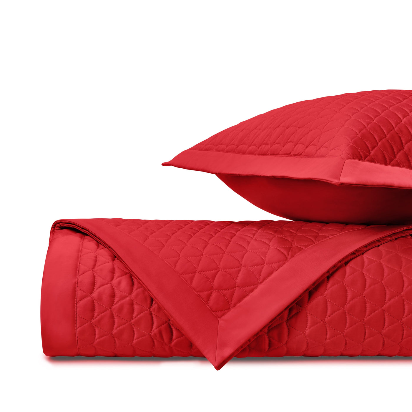 Close-up of crimson quilted diamond pattern with satin binding on folded coverlet and sham.