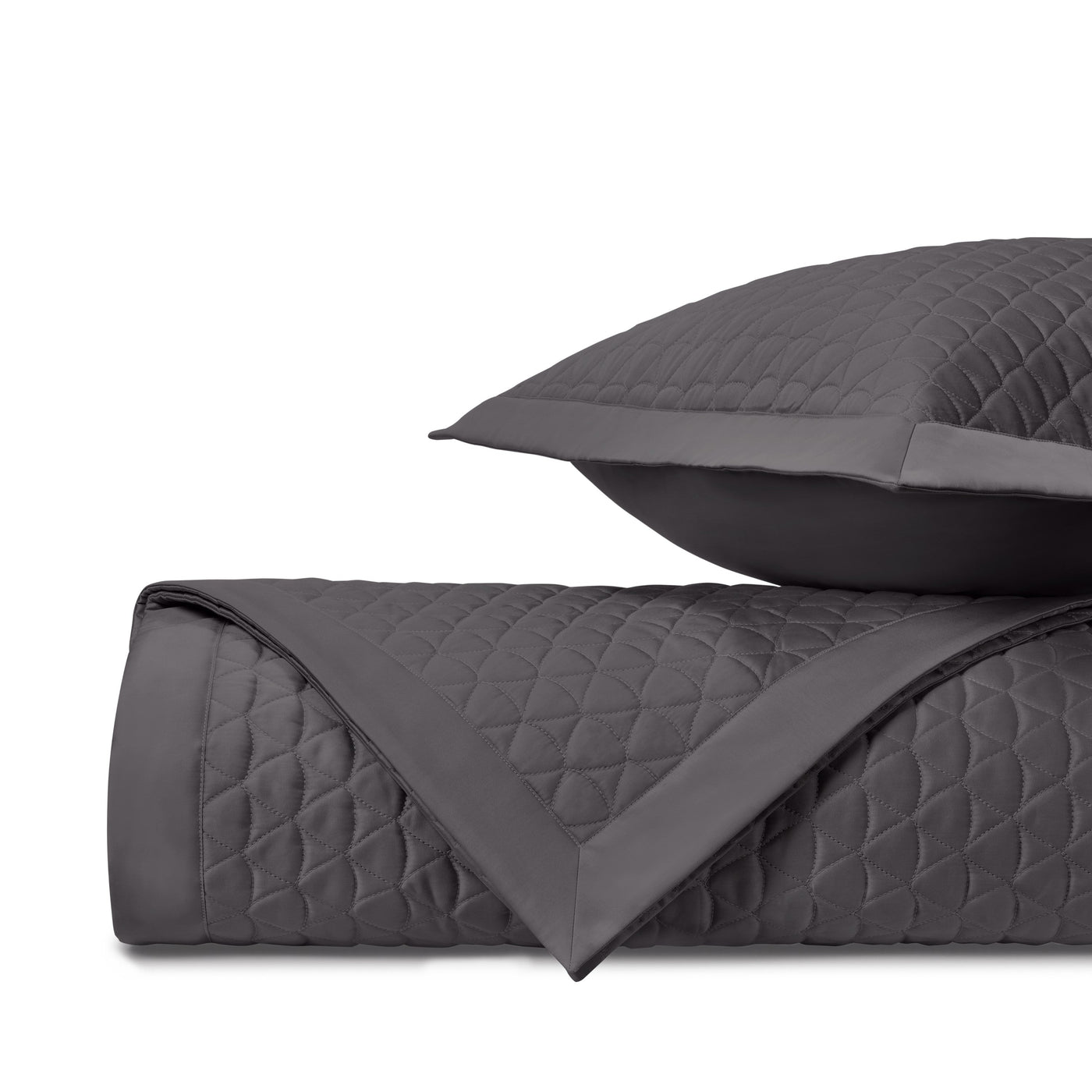 Close-up of charcoal quilted coverlet rolled with diamond stitching and satin border detail.