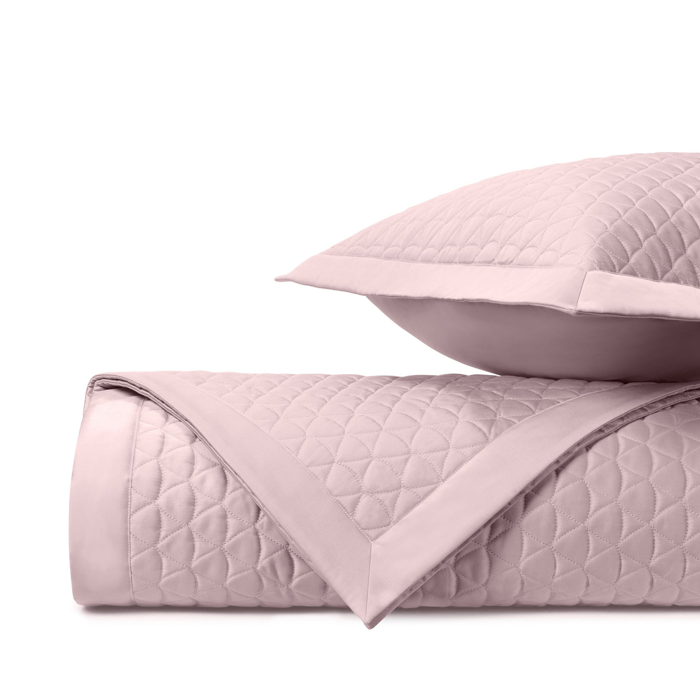 Close-up of blush quilted coverlet with diamond stitching pattern and satin border trim.