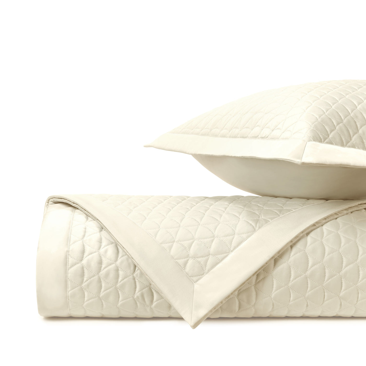 Close-up of ivory quilted diamond-pattern coverlet with satin border trim.