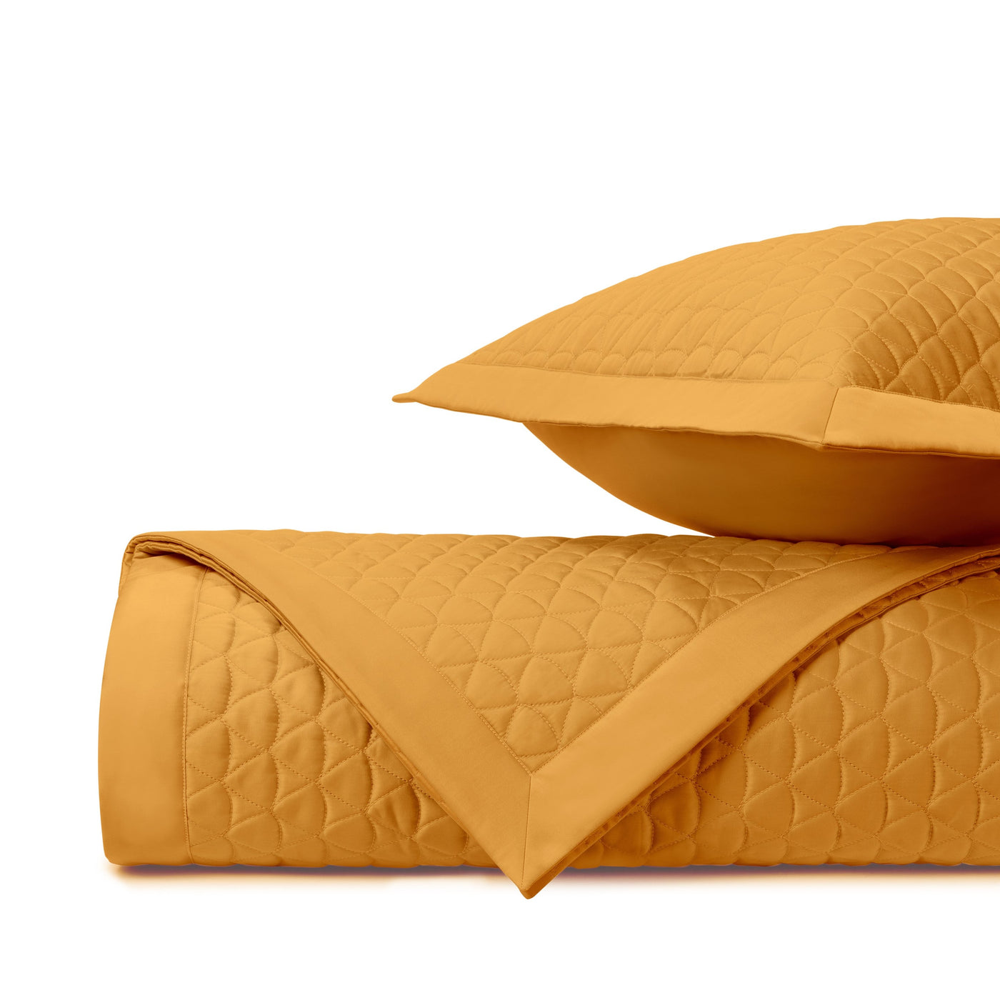 Diamond quilted coverlet rolled and folded beside a matching saffron sham.
