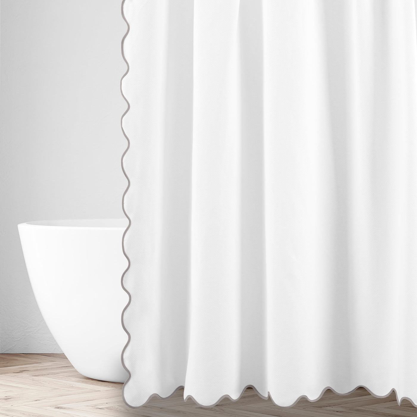 White shower curtain with grey scalloped edge trim, styled in a bathroom setting.