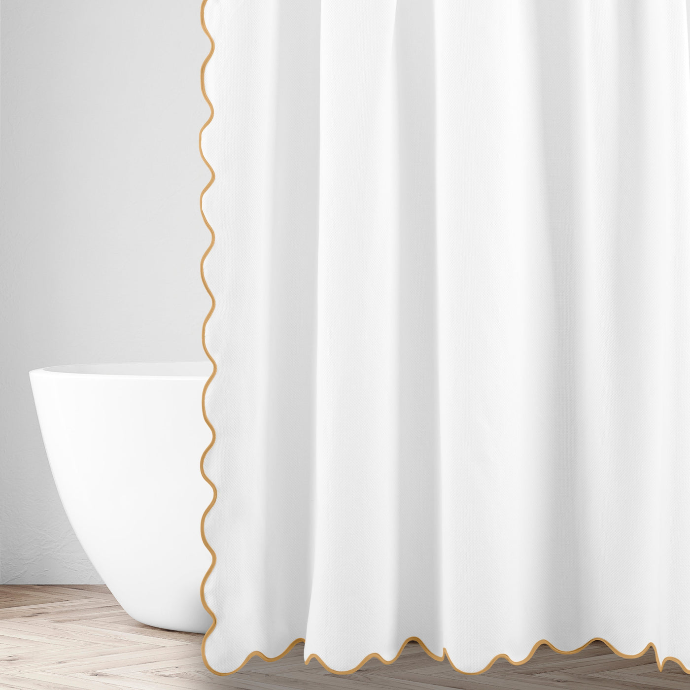 White shower curtain with gold scalloped trim edge, styled beside a freestanding bathtub.