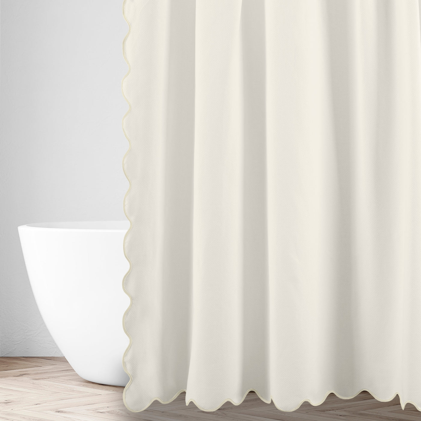 Close-up of ivory linen fabric with scalloped edge detail, styled beside a freestanding bathtub.