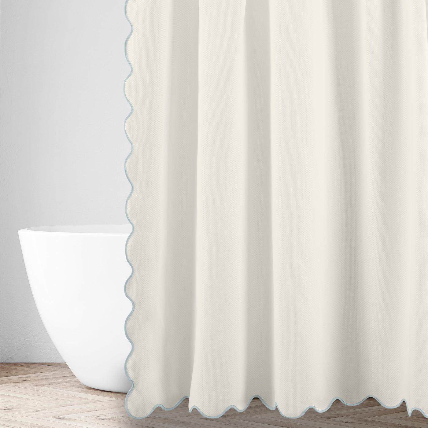Antalya ivory shower curtain with seafoam scalloped edge, styled beside a freestanding tub.