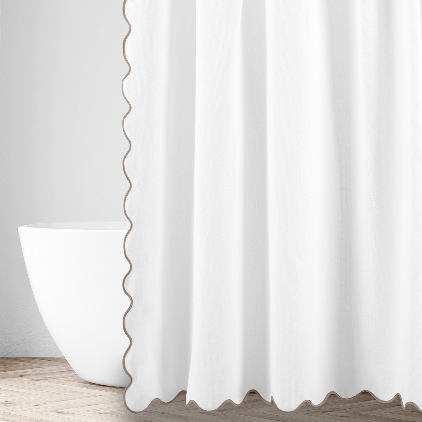 White shower curtain with taupe scalloped trim edge, styled in a bright bathroom with freestanding tub.