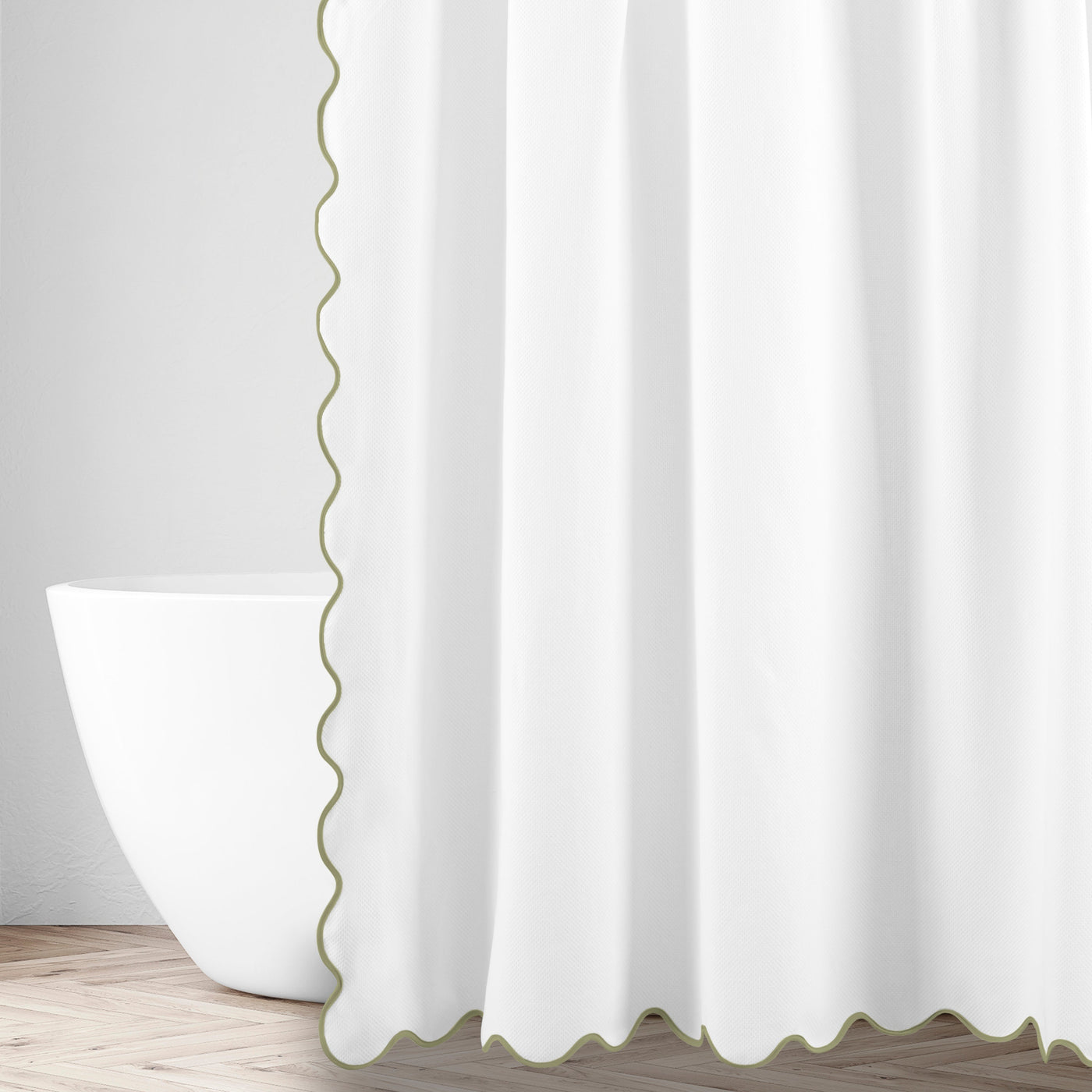 Close-up of white linen with sage scalloped edge trim, draped beside a freestanding tub.