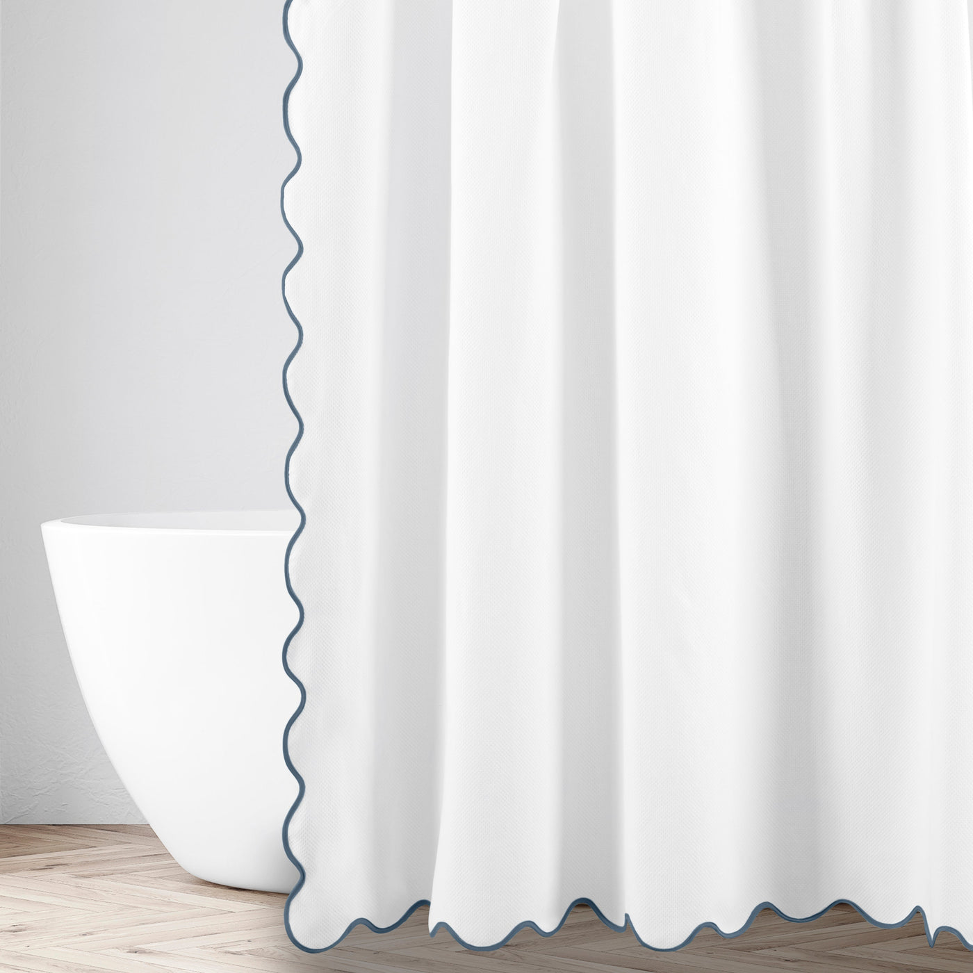 Antalya shower curtain in white with navy scalloped edge trim, hung beside a freestanding tub.