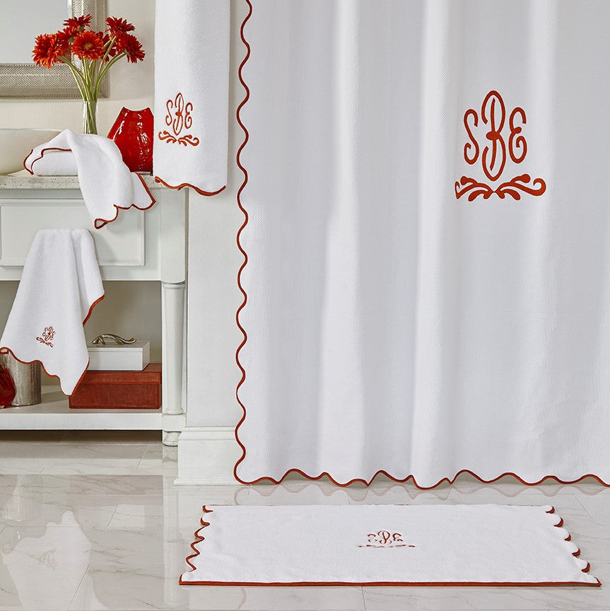 White linen bath set with red scalloped trim and monogram embroidery.
