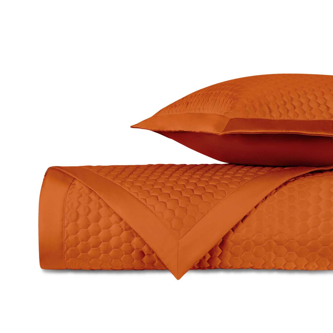 Rolled tangerine quilted fabric with honeycomb texture and satin border, styled with matching pillow.