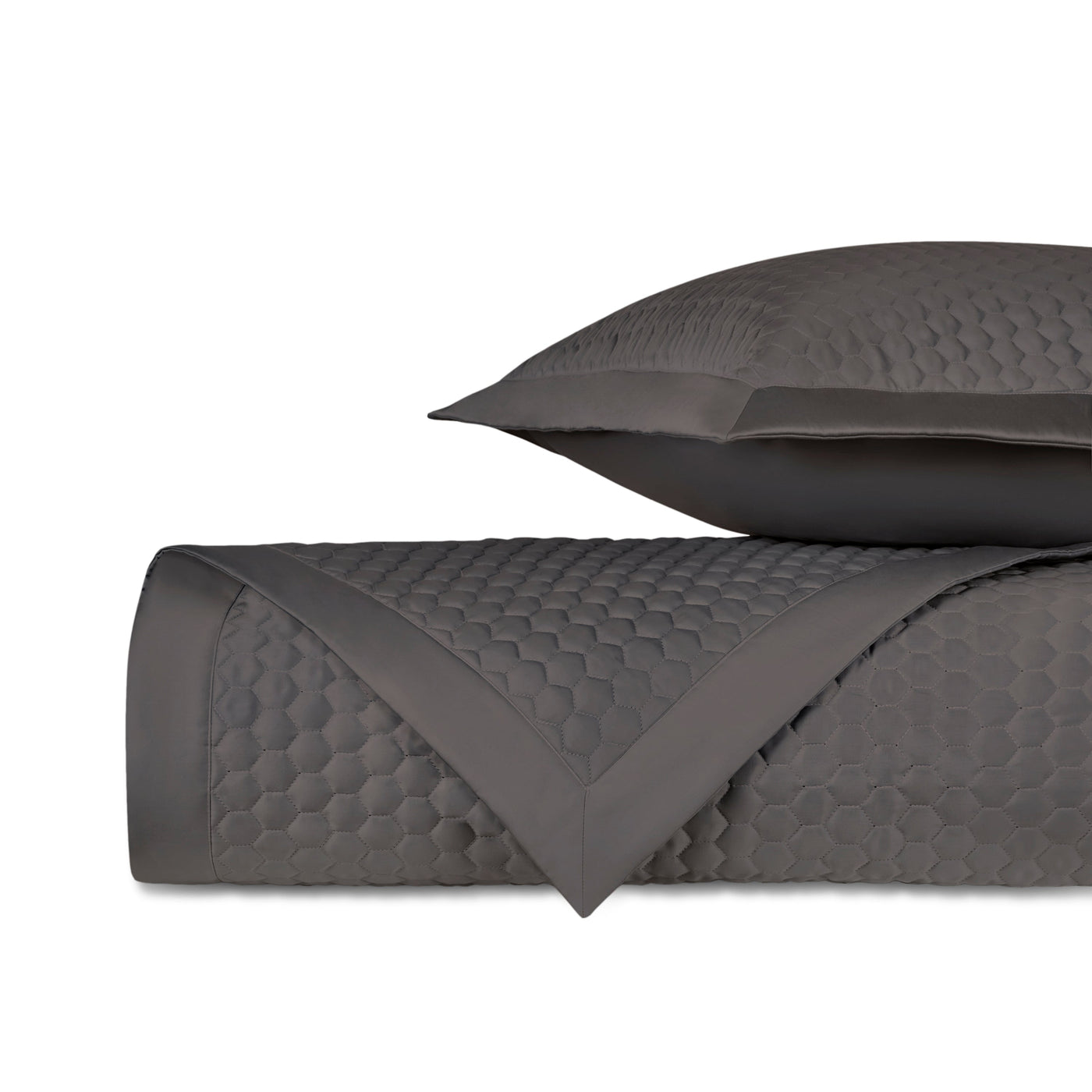 Charcoal quilted coverlet folded with matching sham, honeycomb texture detail visible.