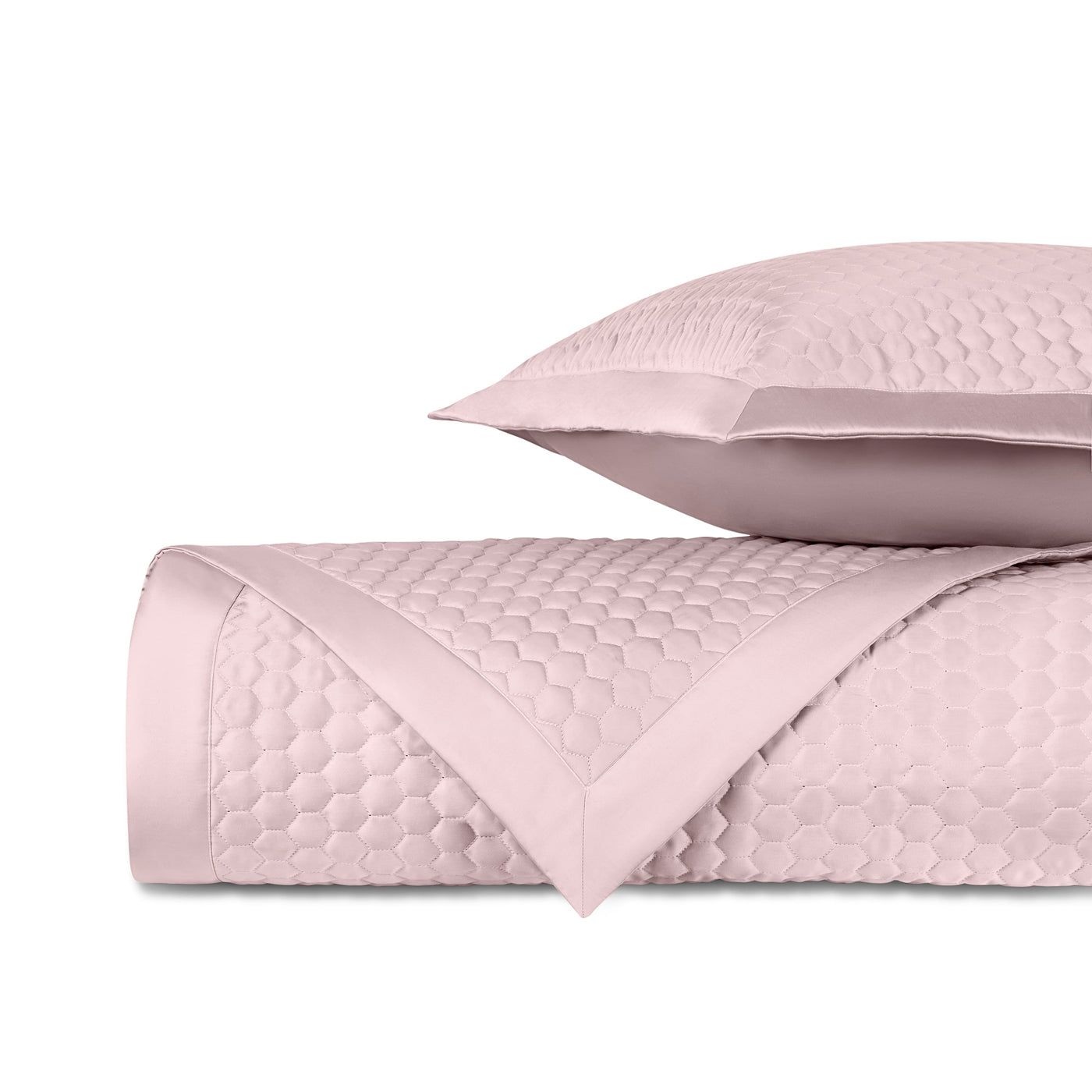Close-up of Apiary quilted coverlet in blush with honeycomb texture and satin trim.