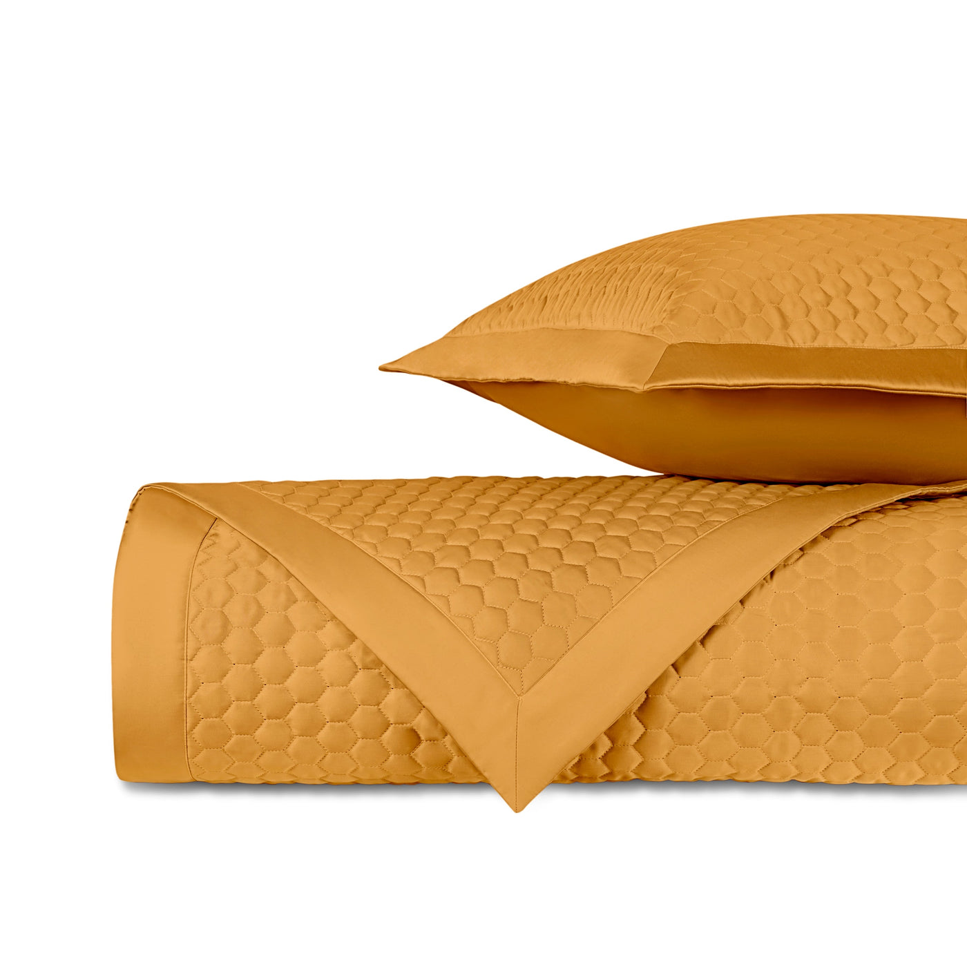 Honeycomb-quilted saffron fabric rolled and stacked with a matching pillow sham.
