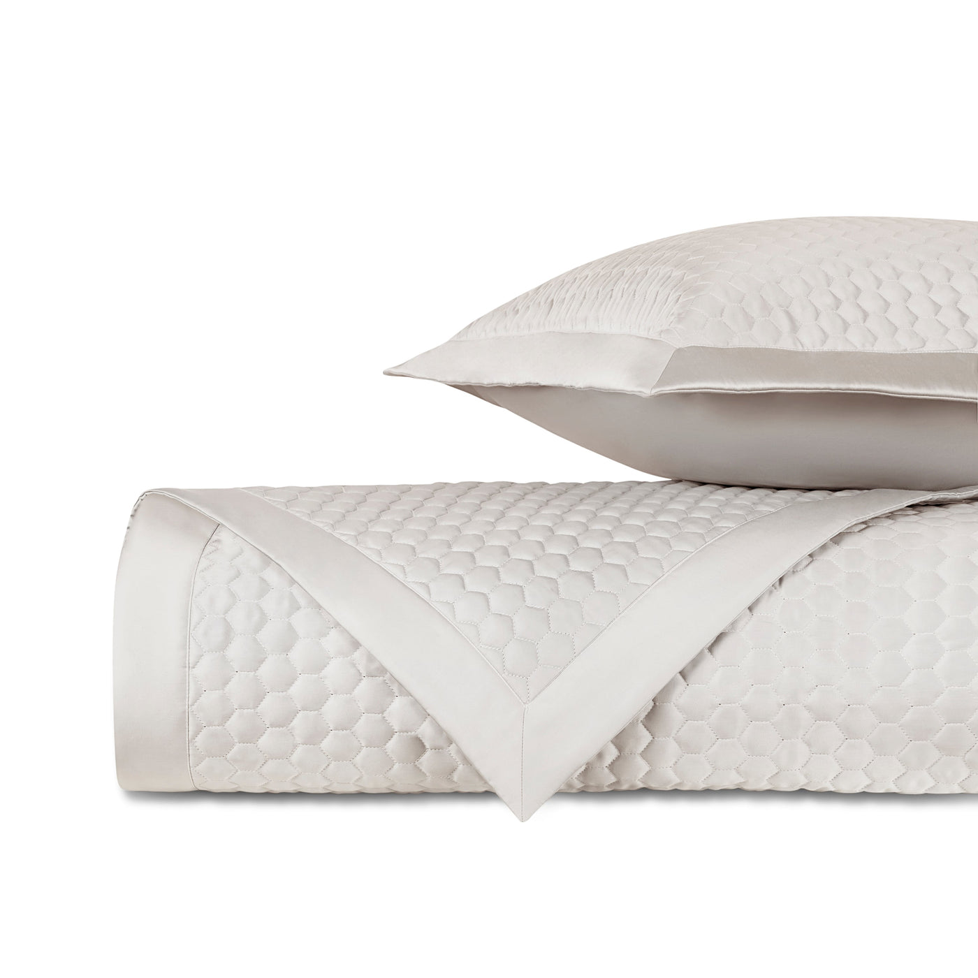 Rolled ivory quilted fabric with honeycomb texture and satin border, styled with matching pillow.