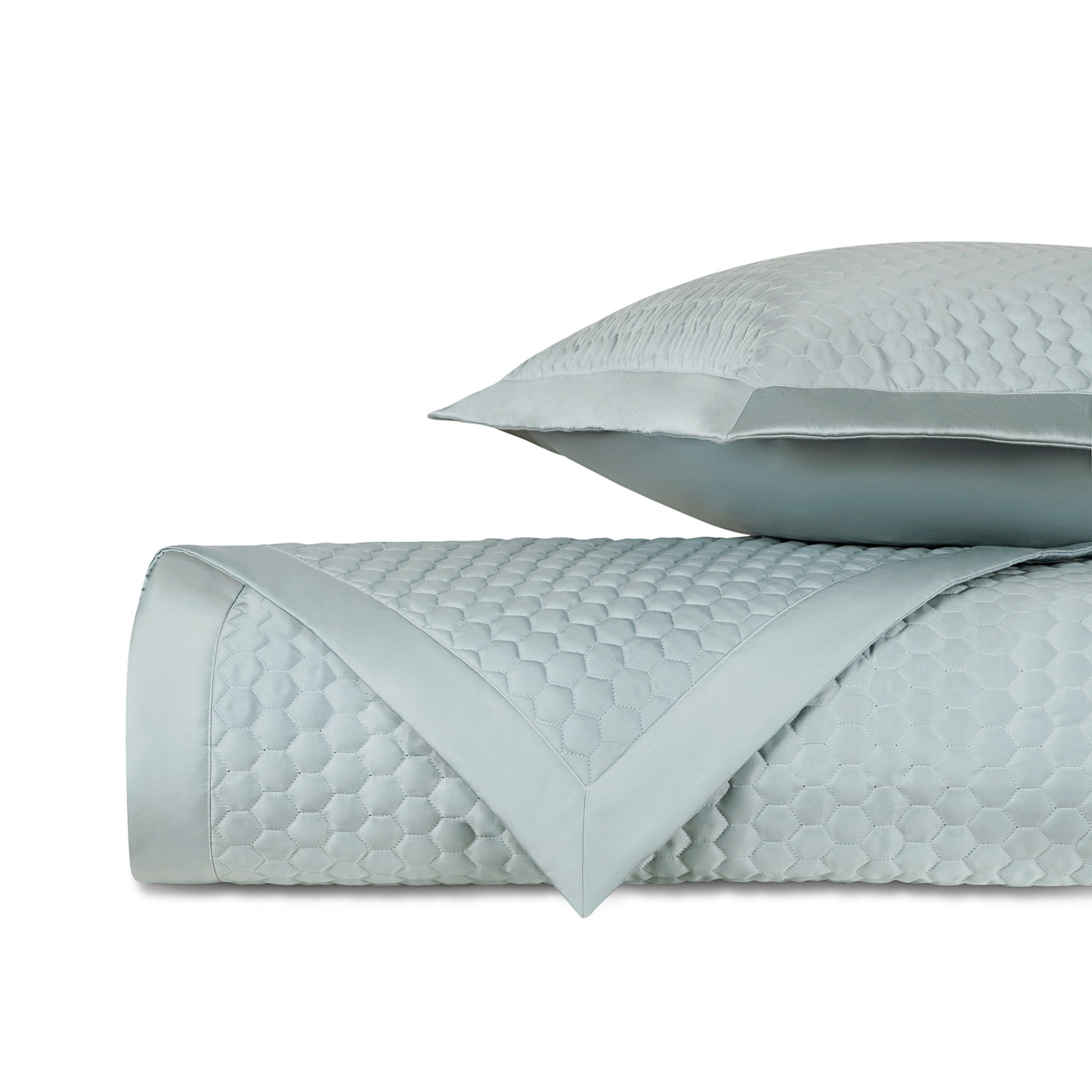 Close-up of Apiary quilted fabric in mist blue with honeycomb texture and satin border trim.