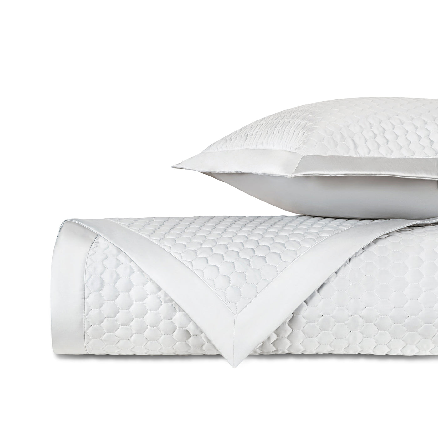 Rolled white quilted fabric with honeycomb texture and satin border, styled with matching pillow.