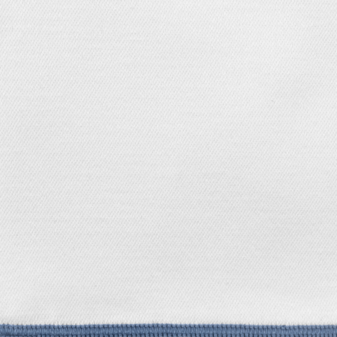 Close-up of white woven fabric with a slate blue blanket-stitched border edge.