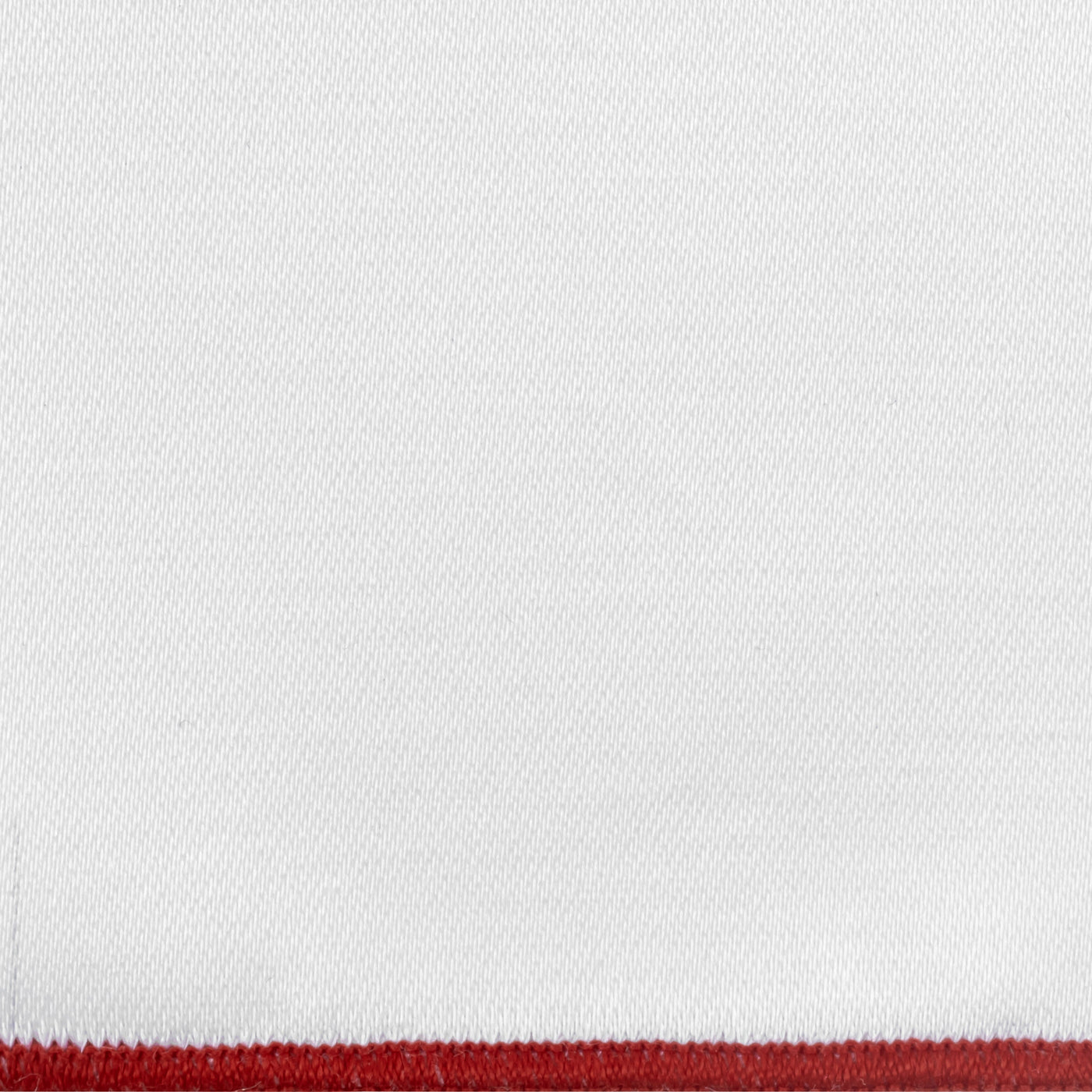 Close-up of white woven fabric with a crimson border trim detail.