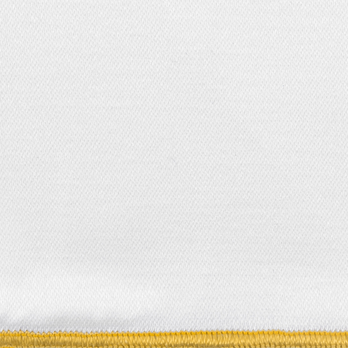 Close-up of white linen weave with a gold embroidered border edge.