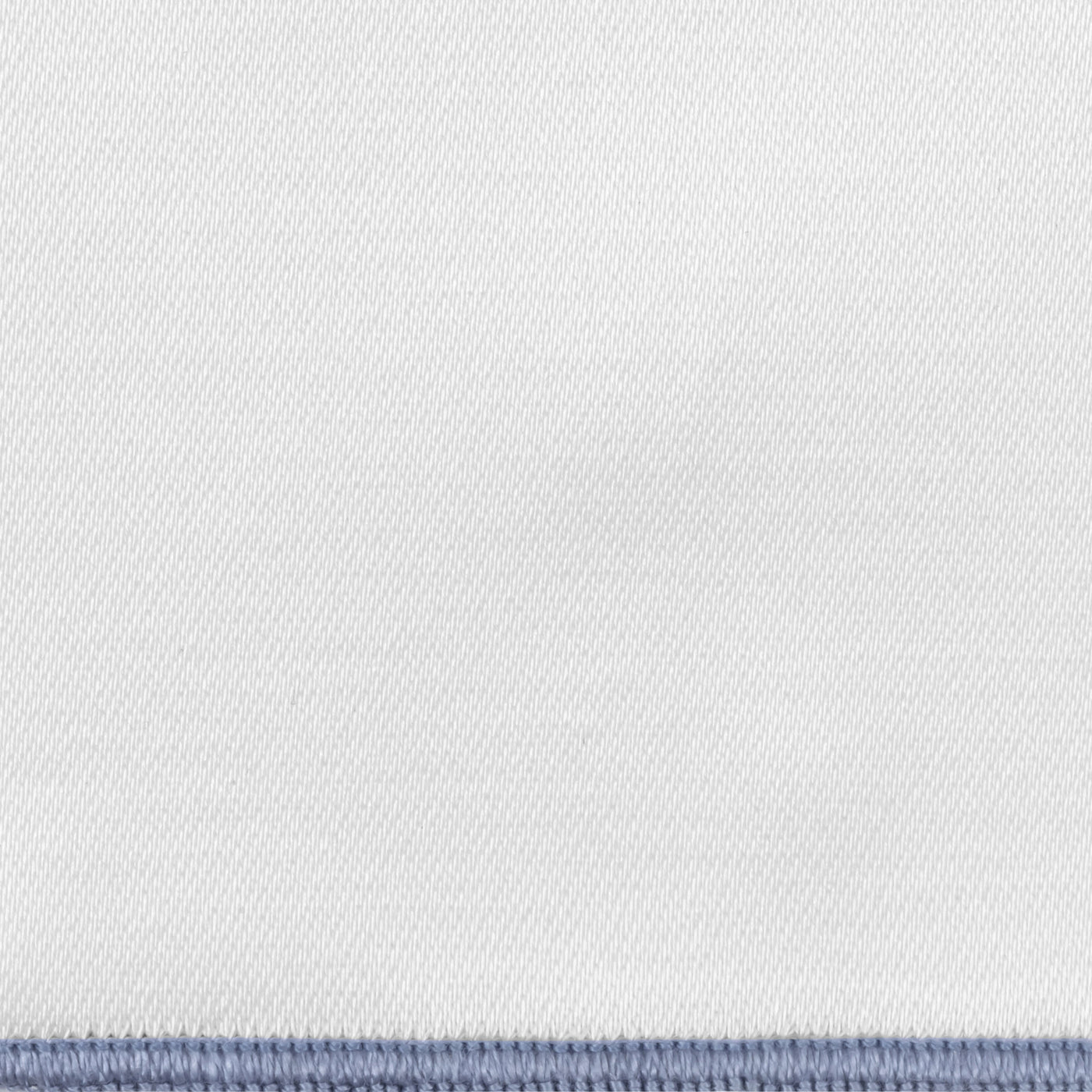 Close-up of white woven fabric with a slate blue blanket-stitched border edge.