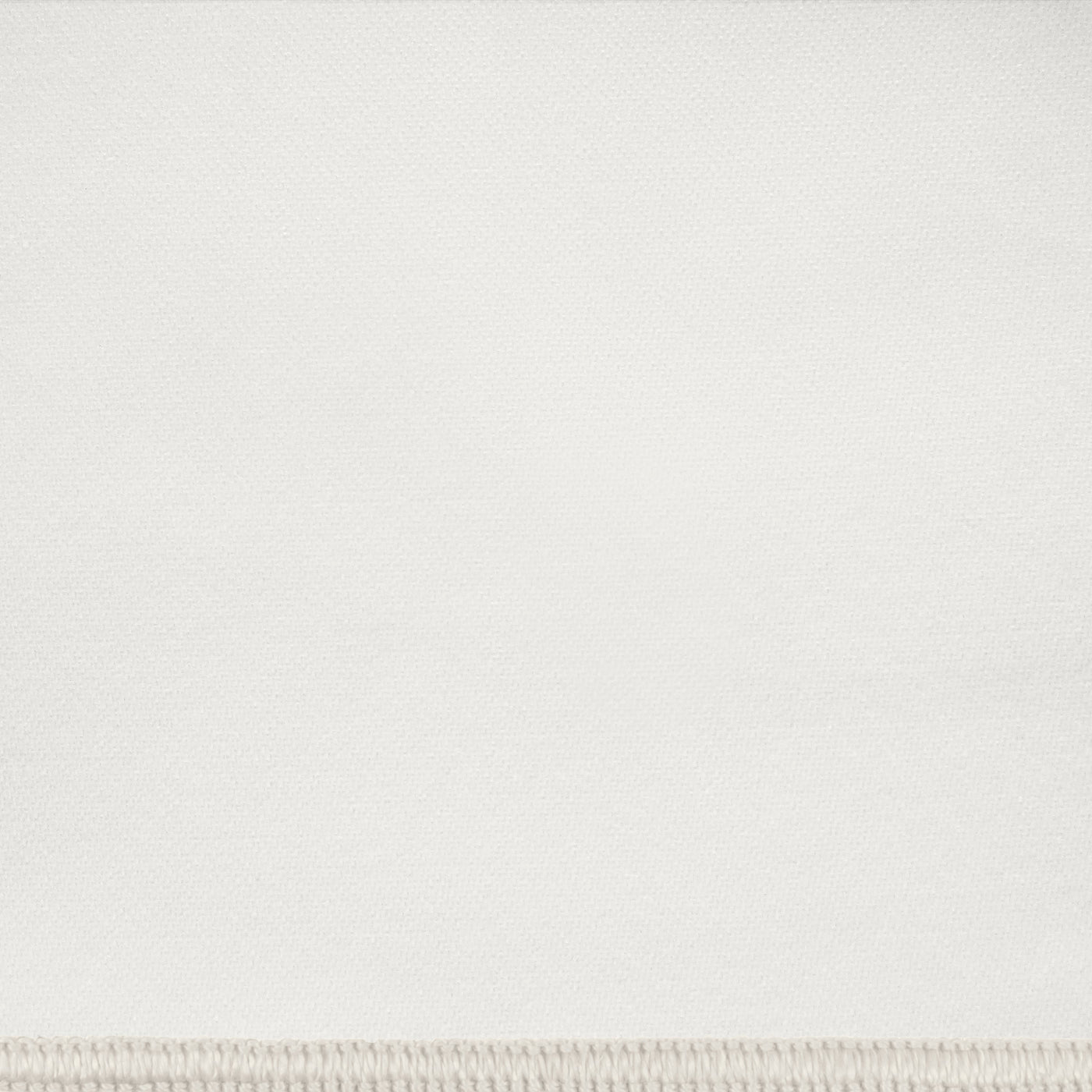 Close-up of ivory woven fabric with a subtle ribbed border edge.