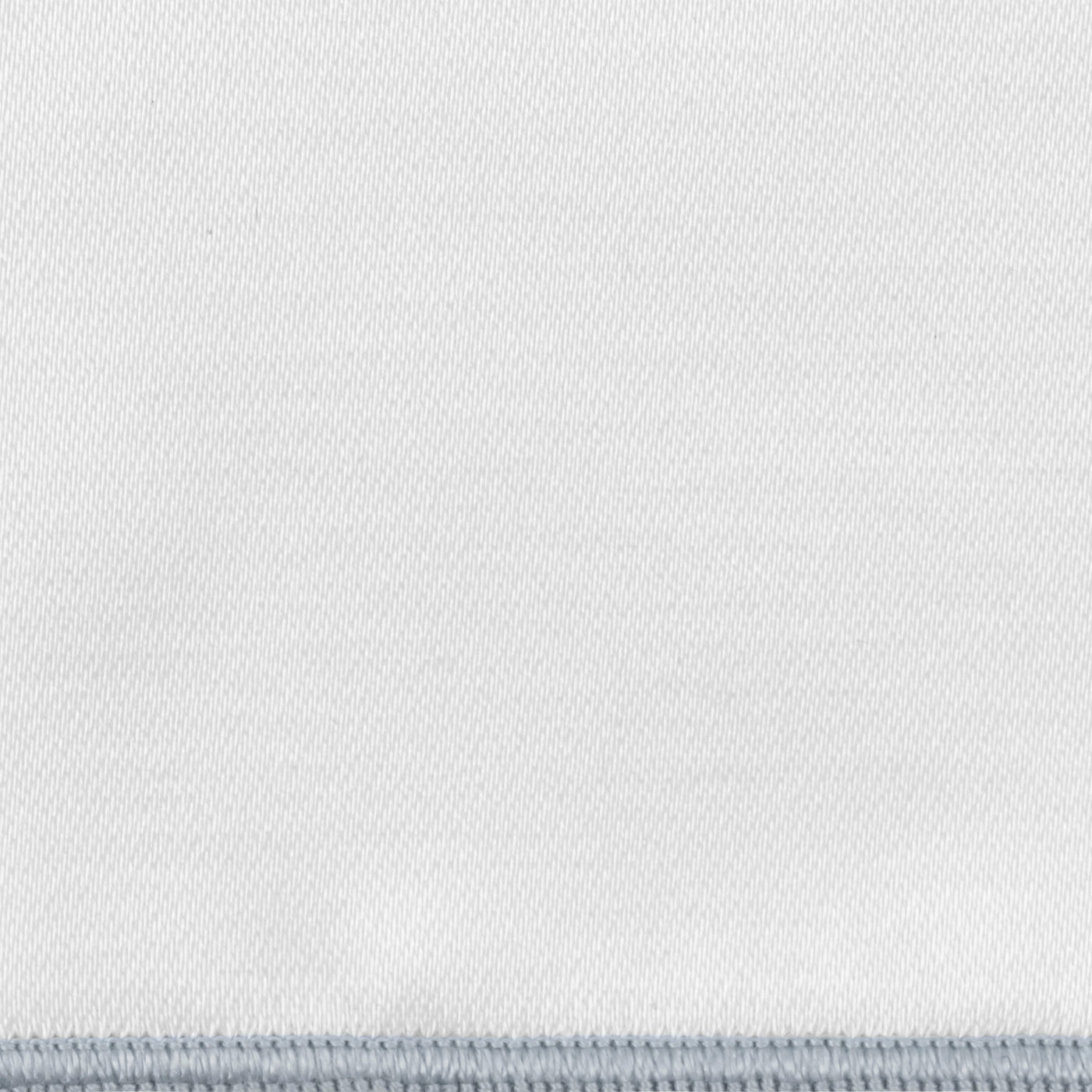Close-up of white woven fabric with a pale silver blanket-stitch border edge.