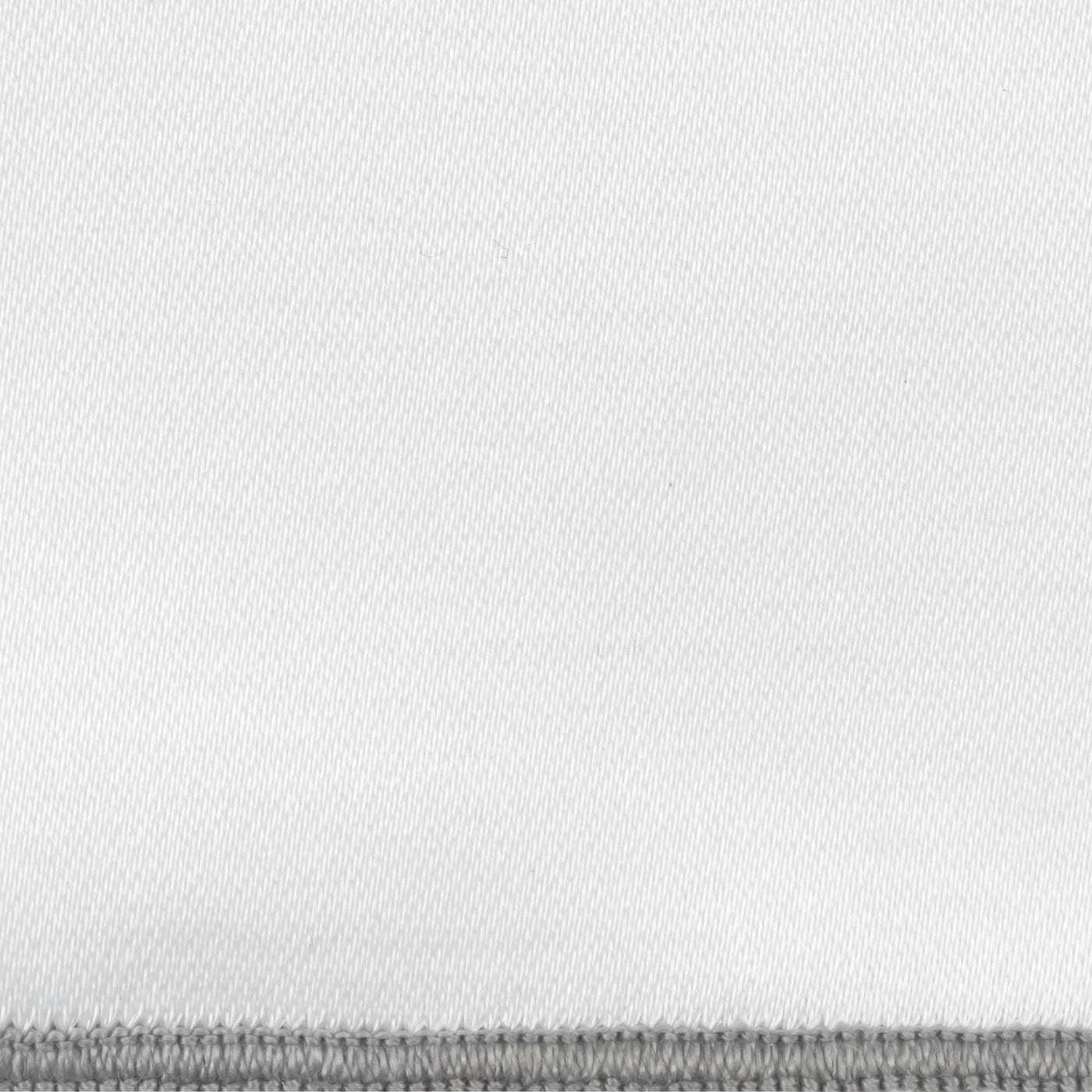 Close-up of white woven fabric with a grey blanket-stitched border edge.