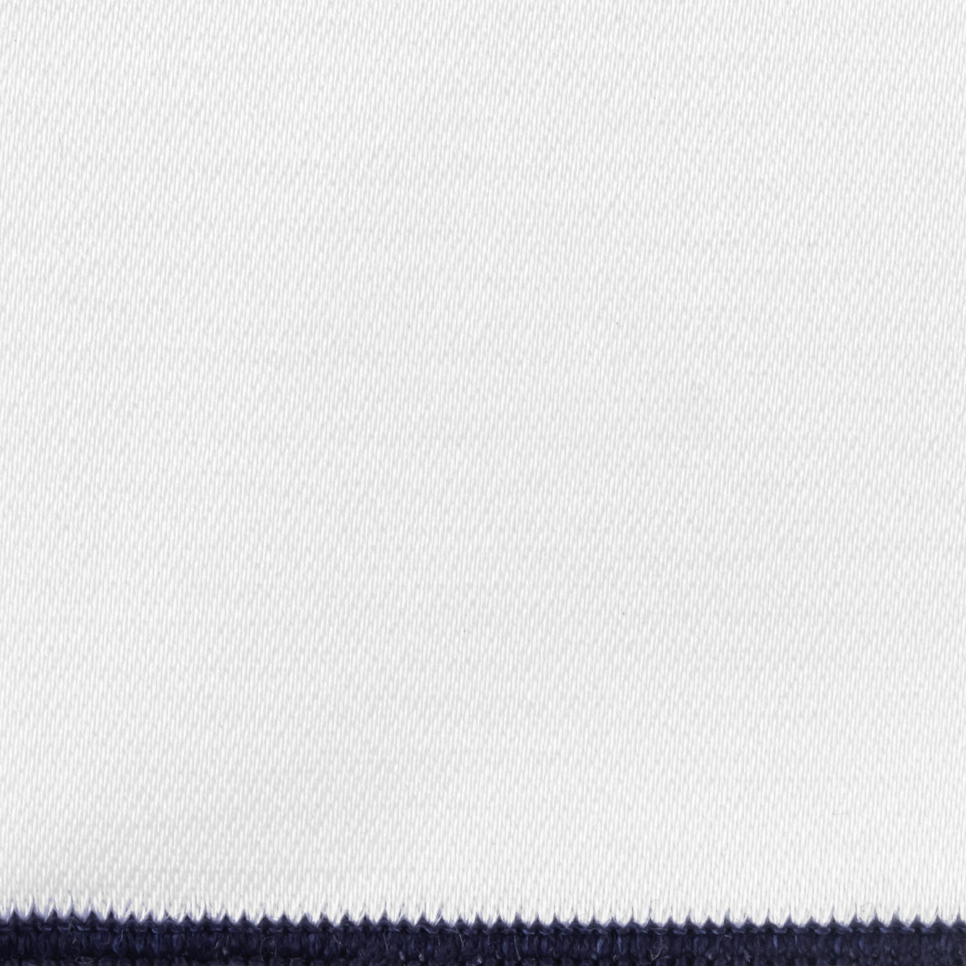 Close-up of white woven fabric with navy contrast border edge.