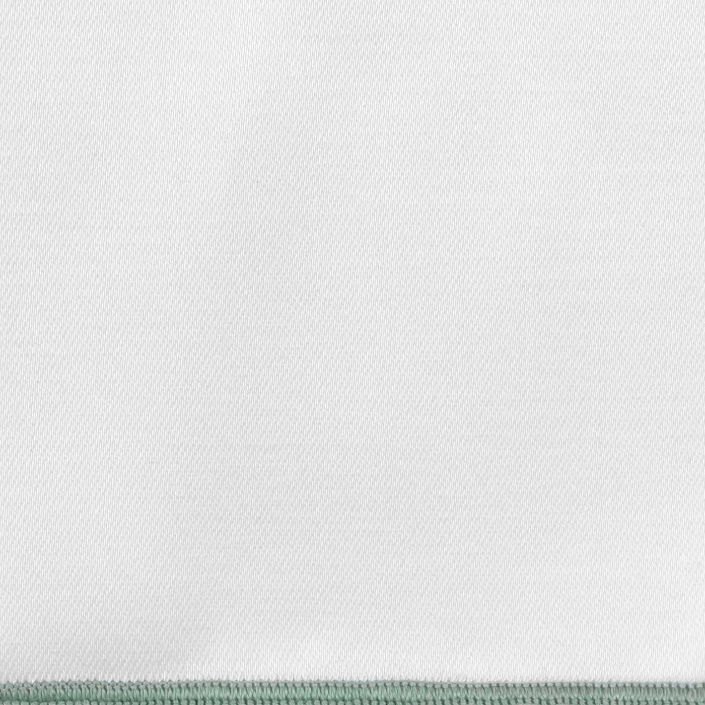 Close-up of white woven fabric with a sage green blanket-stitched border edge.