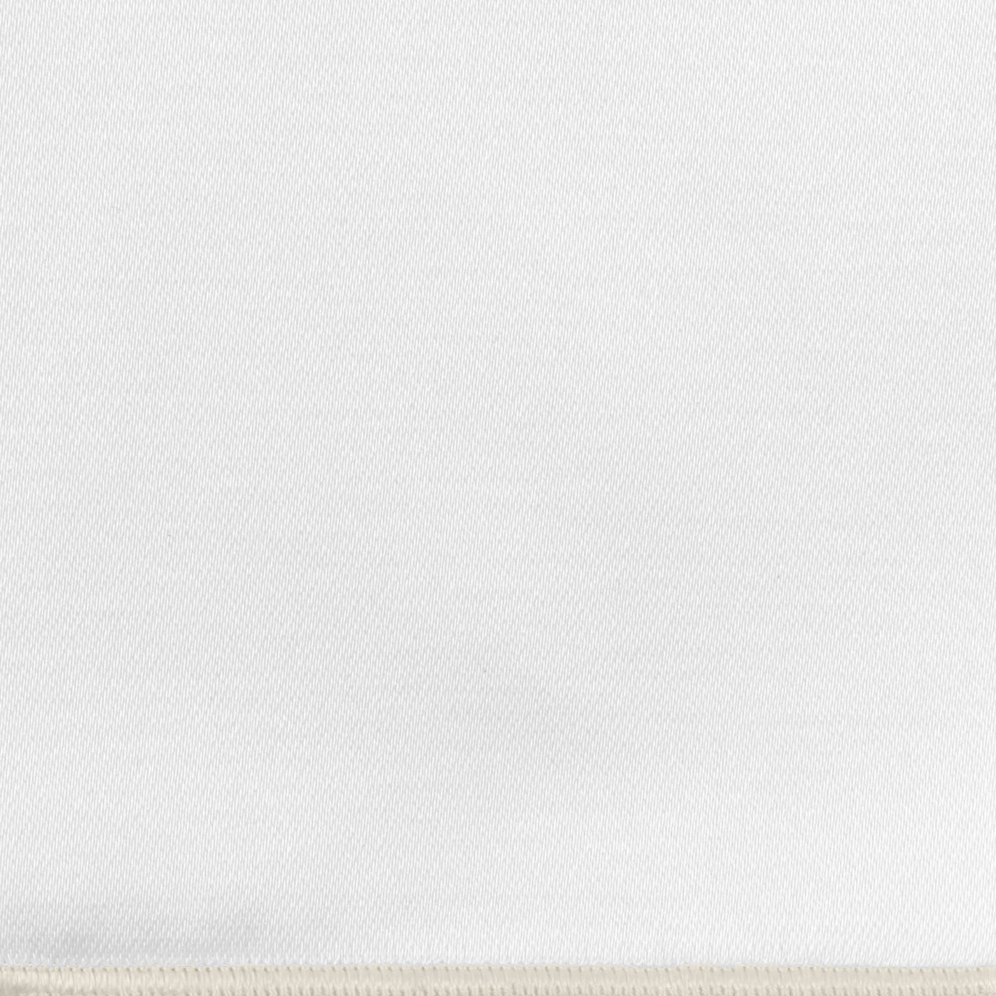 Close-up of ivory woven fabric with subtle diagonal texture and blanket-stitched edge.