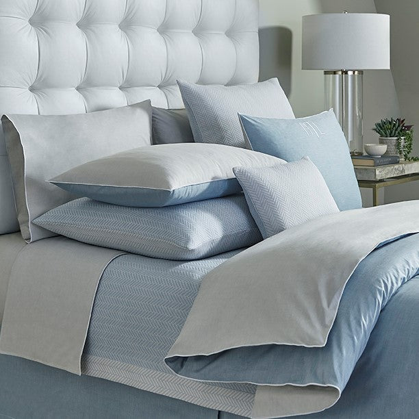 Home Treasures Asher bedding in pale blue and silver grey, styled on a tufted bed.